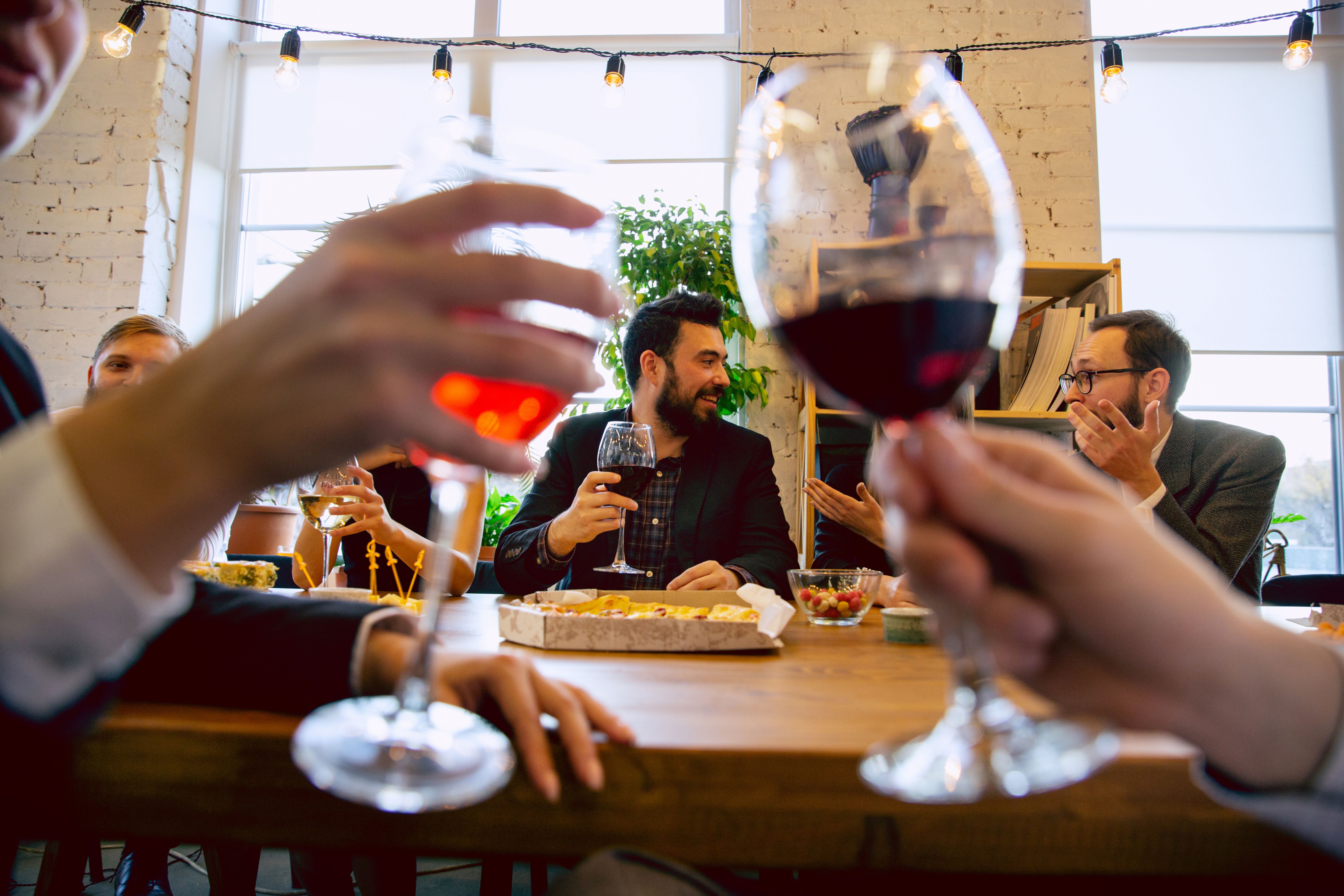  A group of neighbours having food and drinks at a party with plants and a shelf in the background