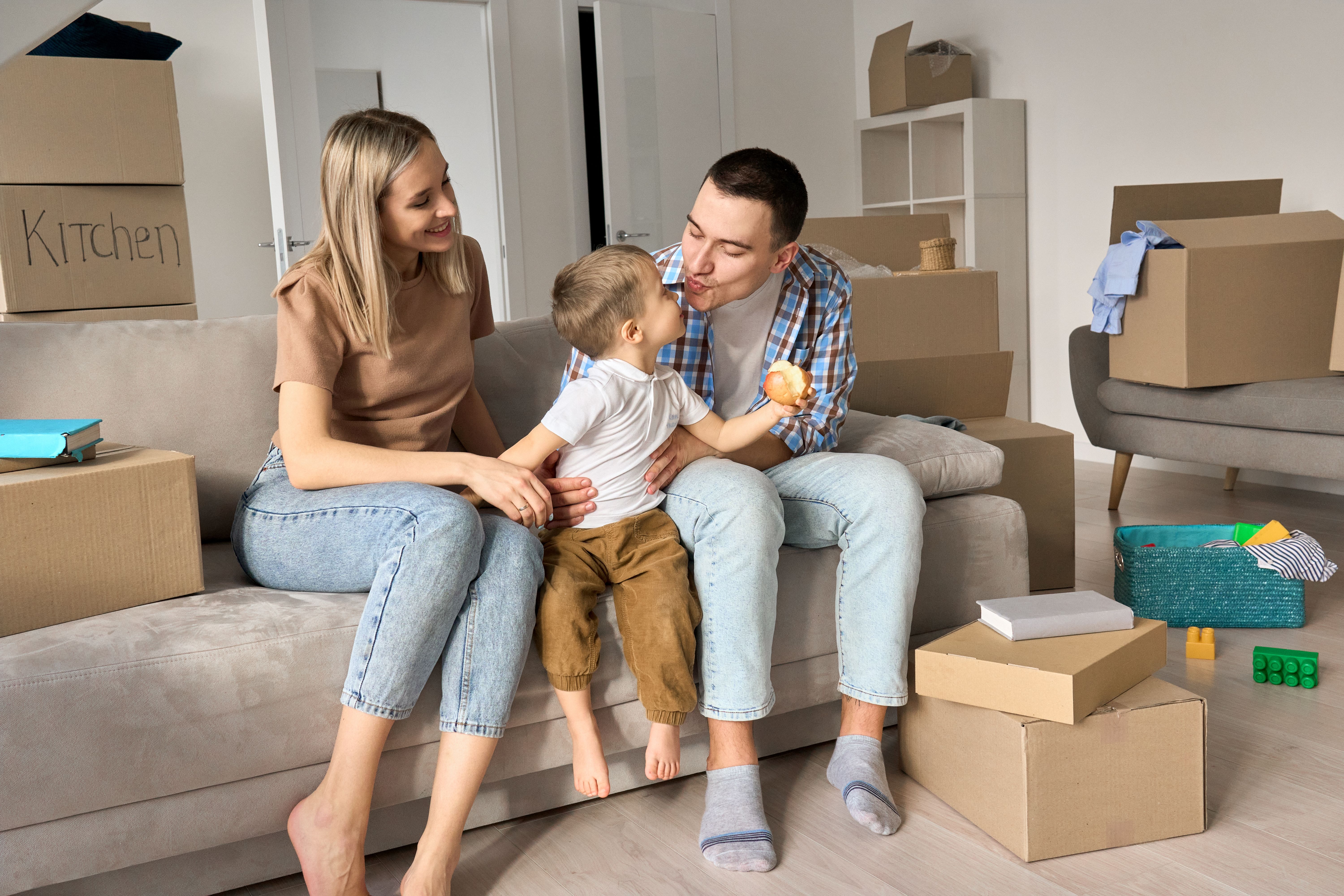 A yappy young parents sitting on a sofa with their kid