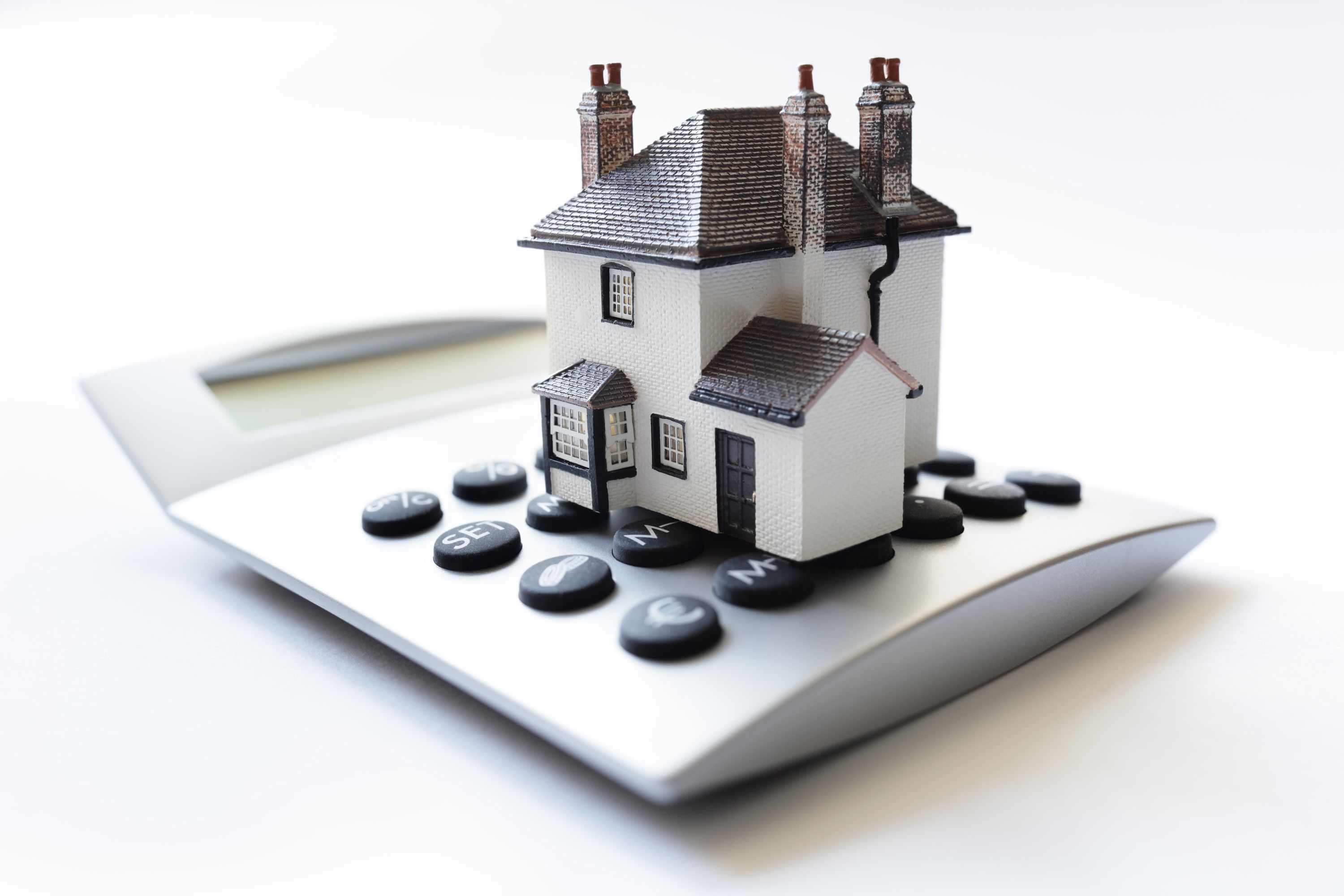 A white and grey house model on top of a calculator.