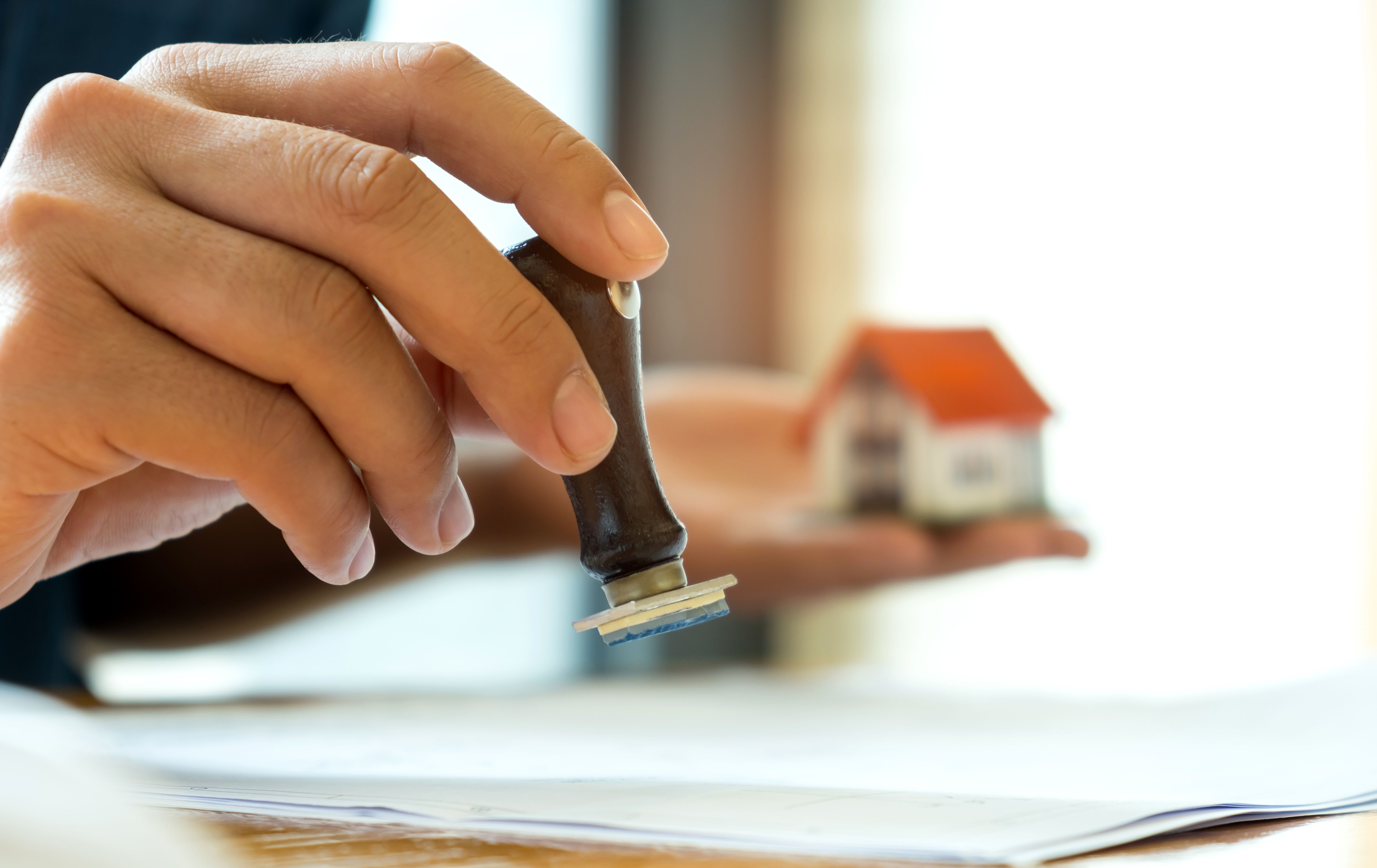 A right hand holding a stamp to stamp approval to clear a Right To Rent check based on tenant's passport