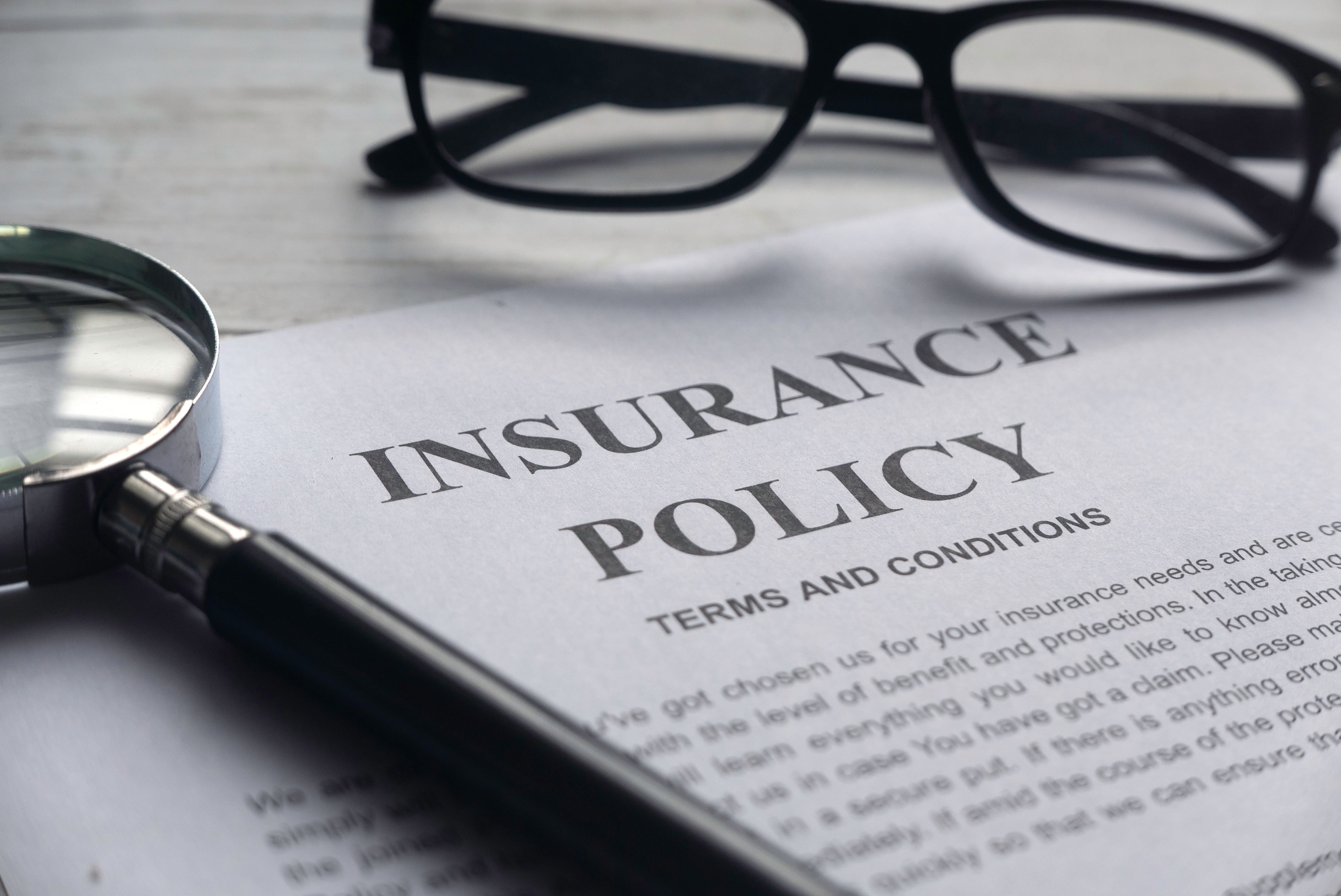 A insurance policy document with a pair of glasses and a magnifying glass