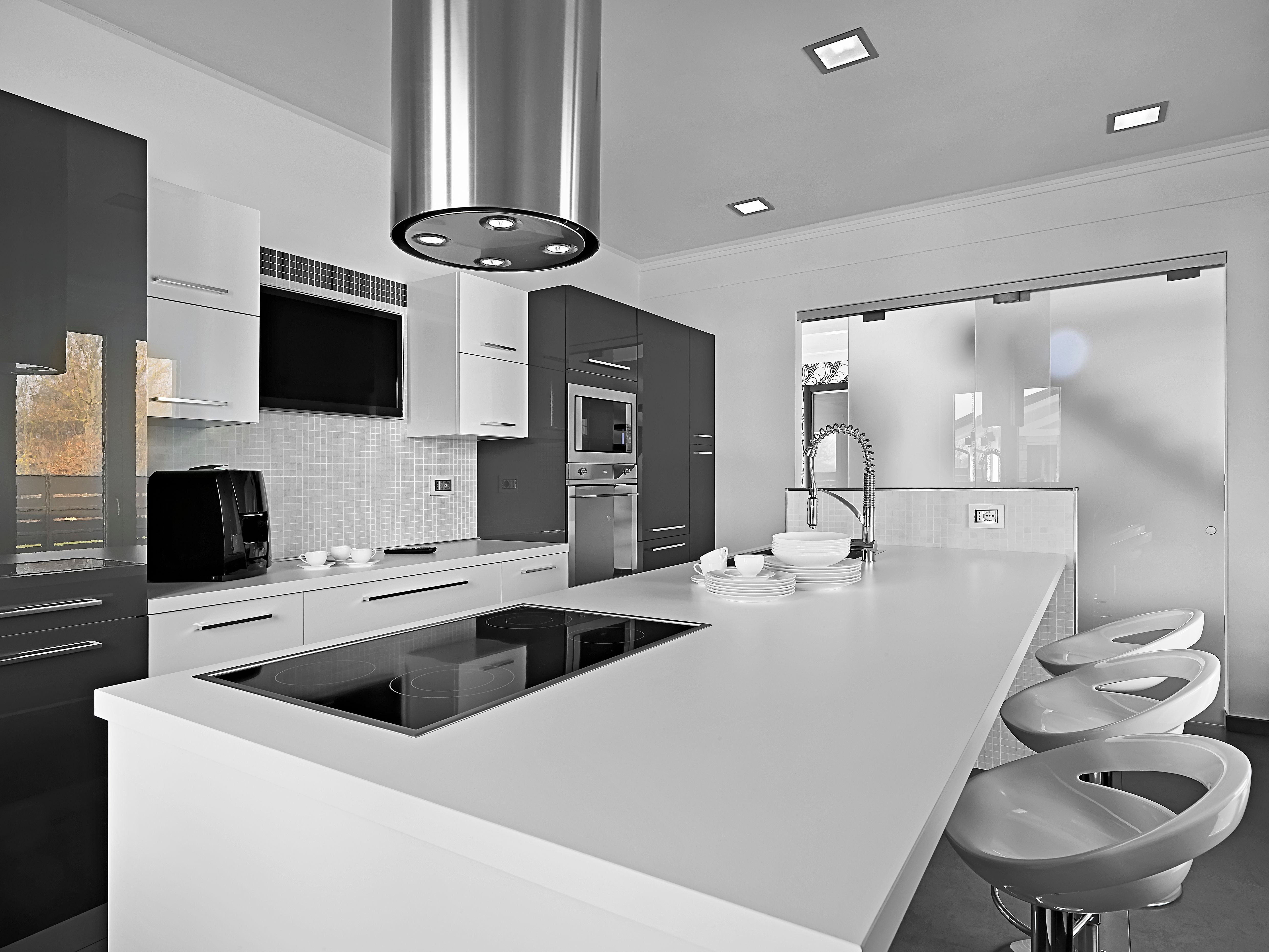  A modern kitchen with a hob, a kitchen island, a sink, a microwave, a refrigerator and chairs .jpg