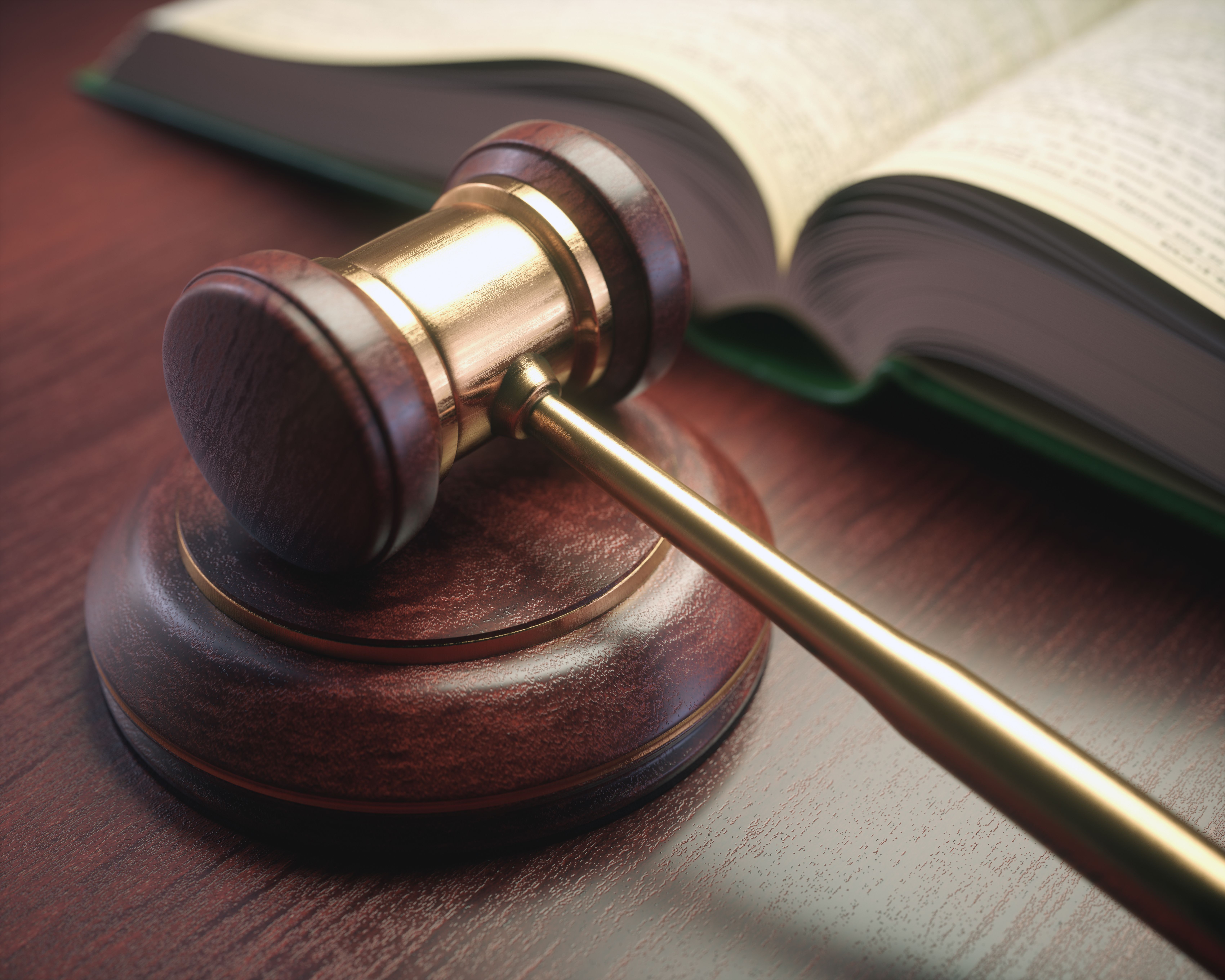 Wooden judge hammer with golden details and a legislation book beside