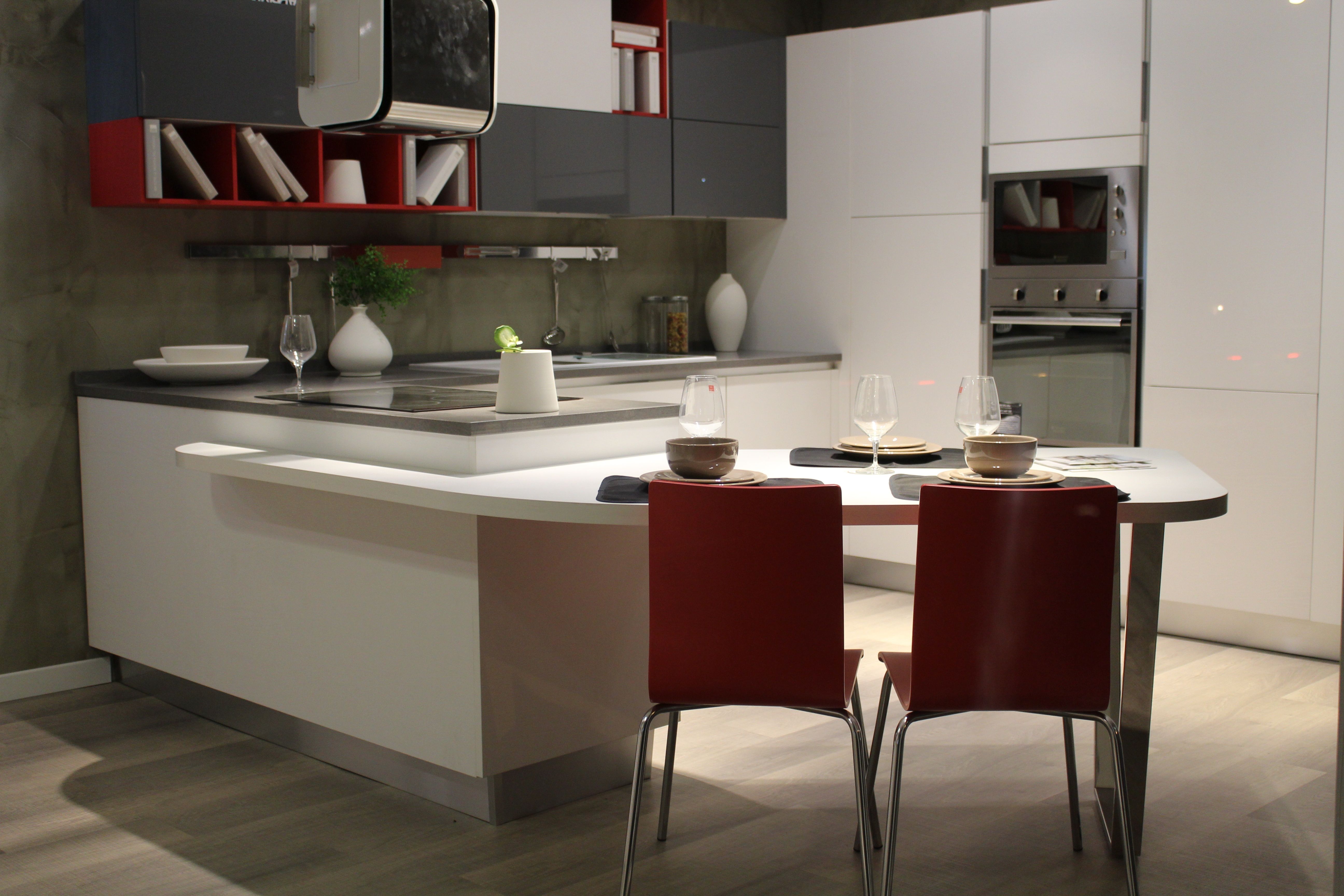 A brand new kitchen with red metal chairs, white kitchen appliances, books on the shelf and white bowl and plate sets.