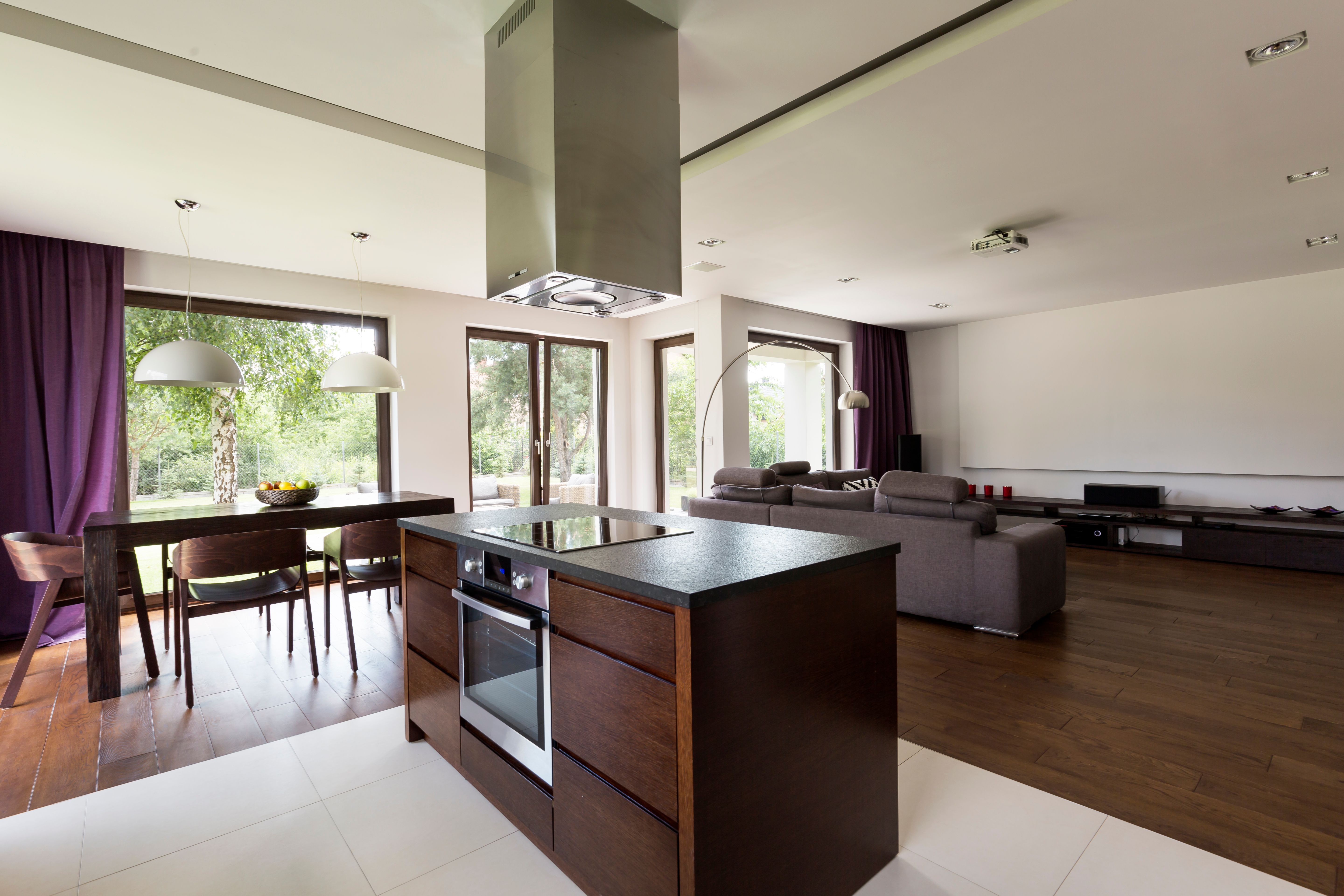 A kitchen island in the centre of an open space in a home with furniture, lamps, and windows in the background.jpg