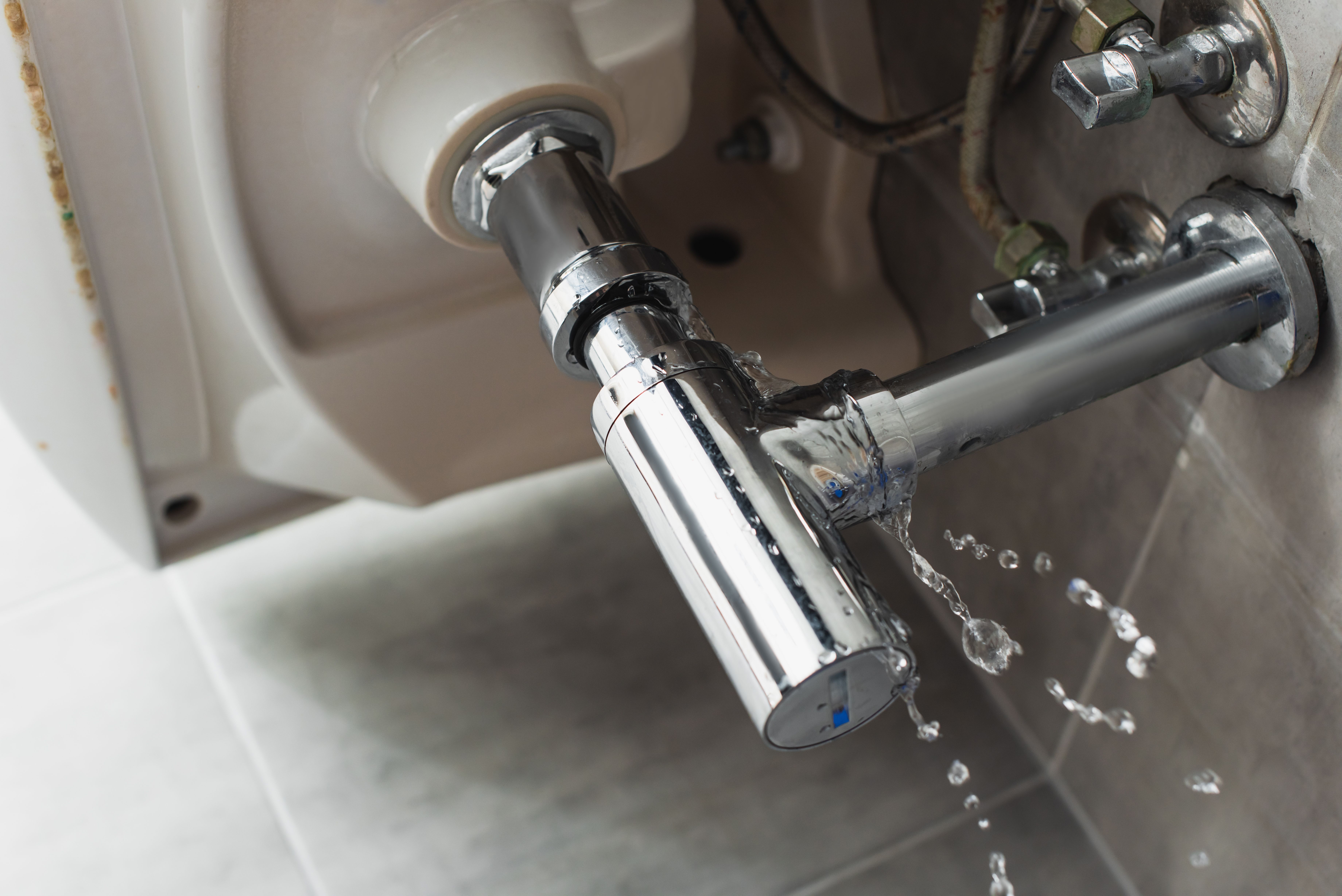 Leaking steel pipe under the sink with water drops