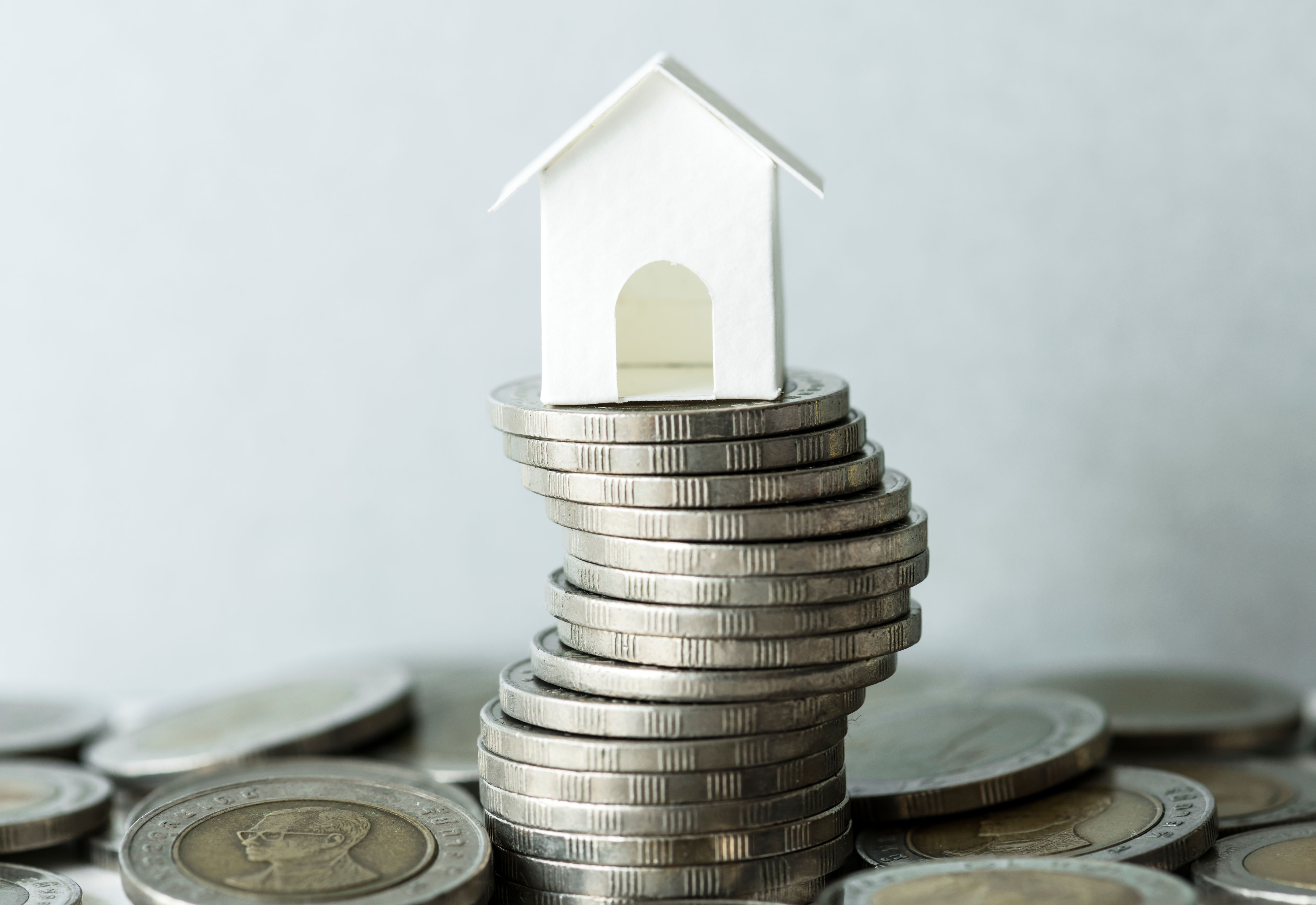 A toy house sitting on top of a pile of coins