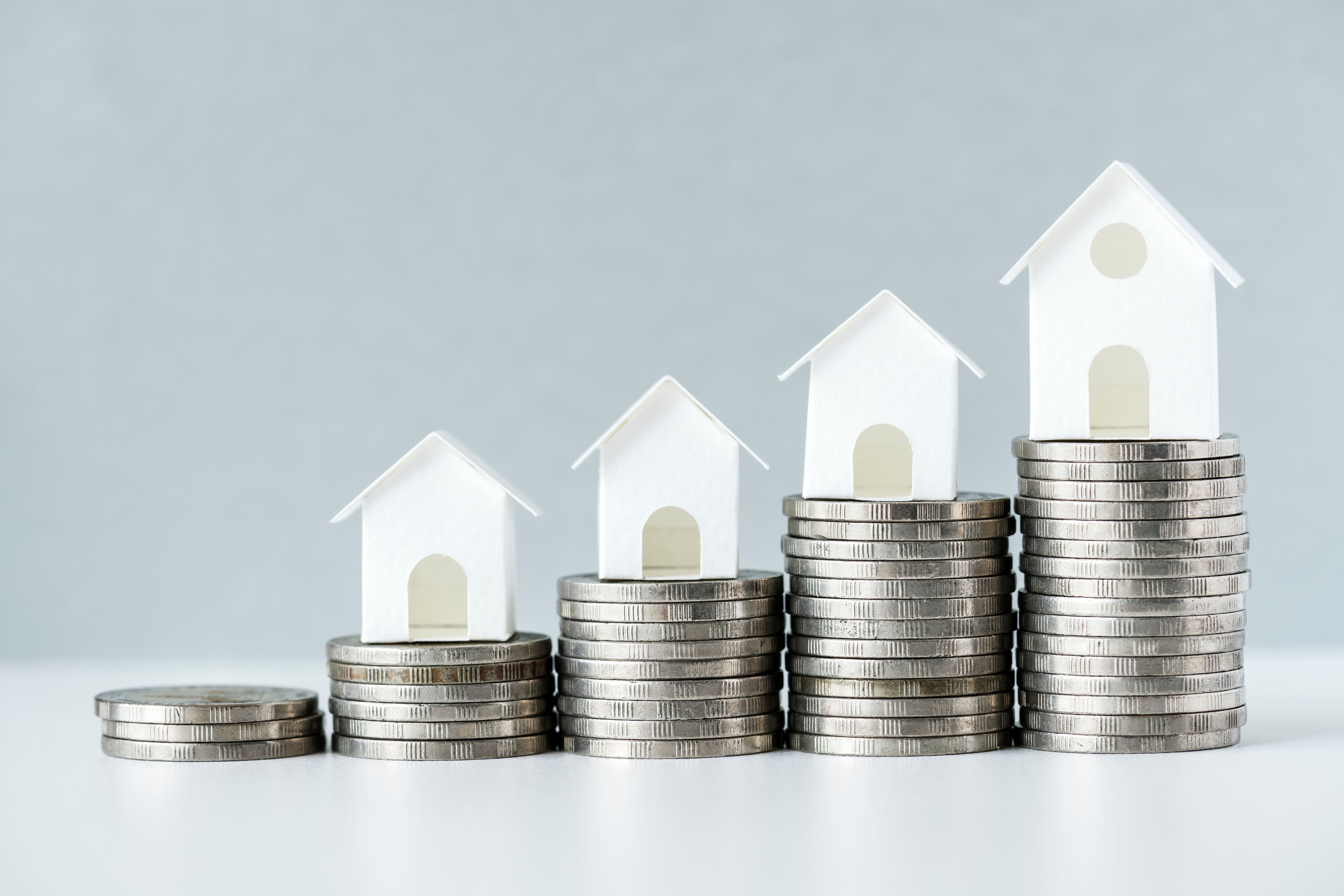 Model houses sitting on top of piles of coins