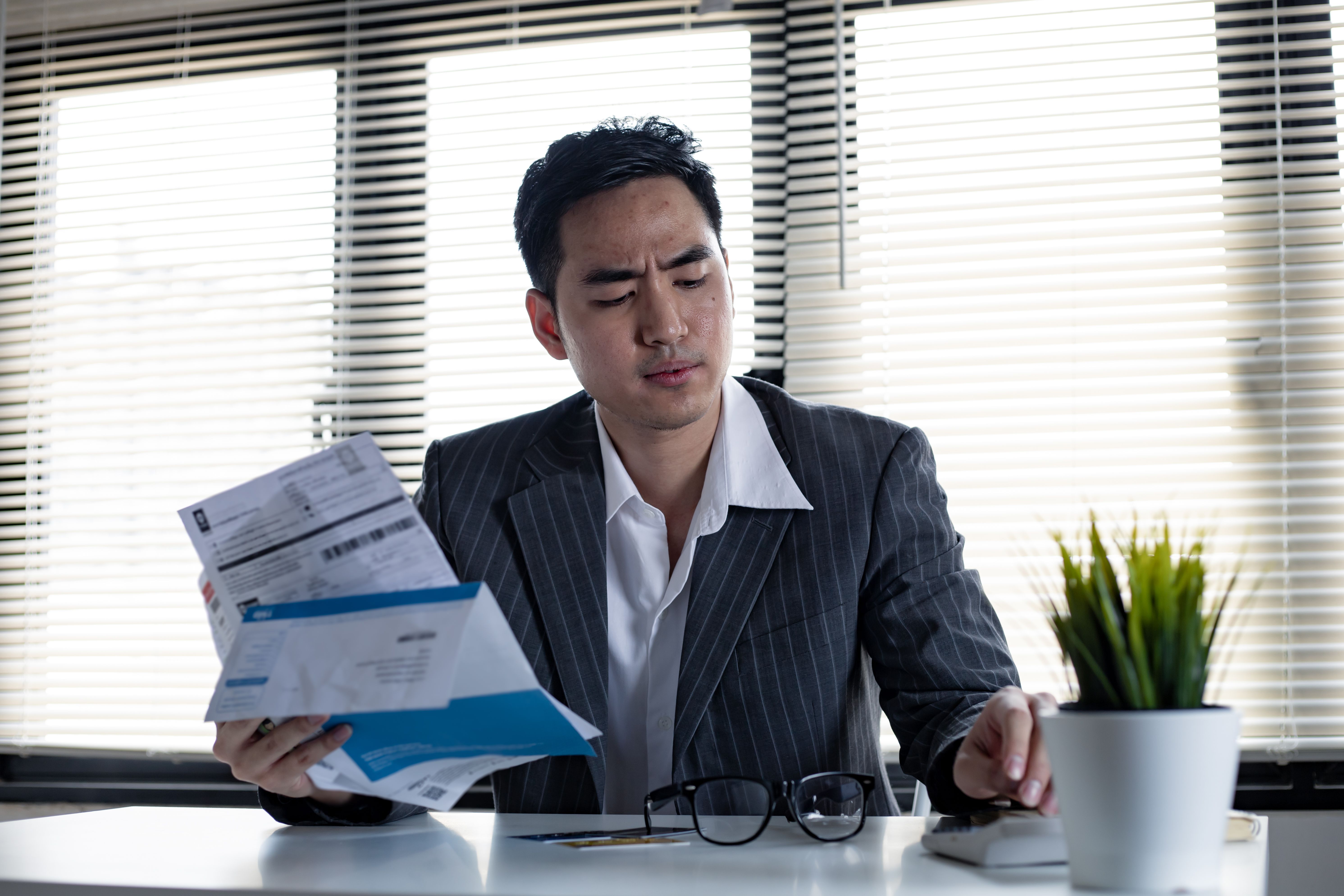 A man calculating his debt at hand with a calculator