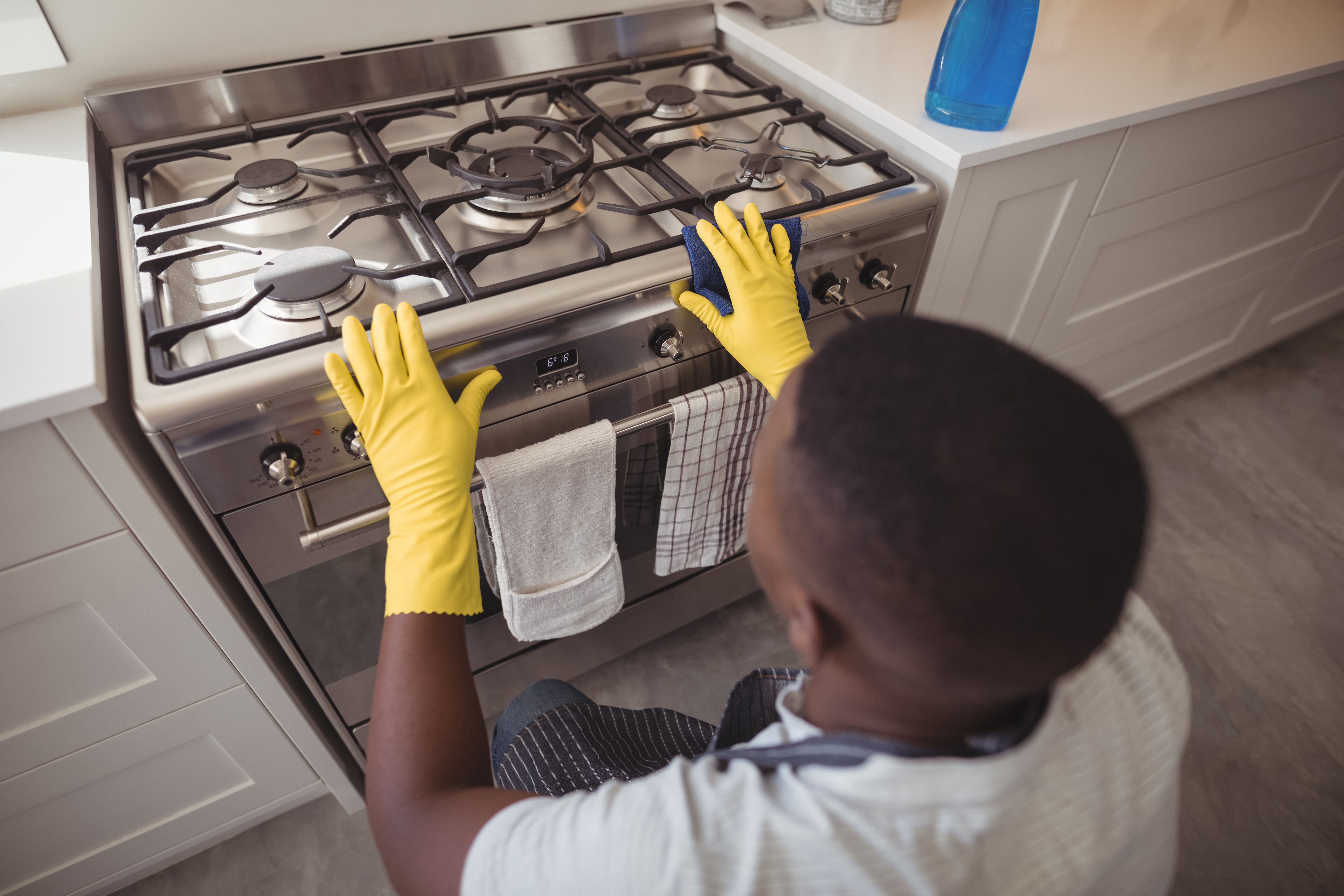 A man checking a gas stove in a kitchen