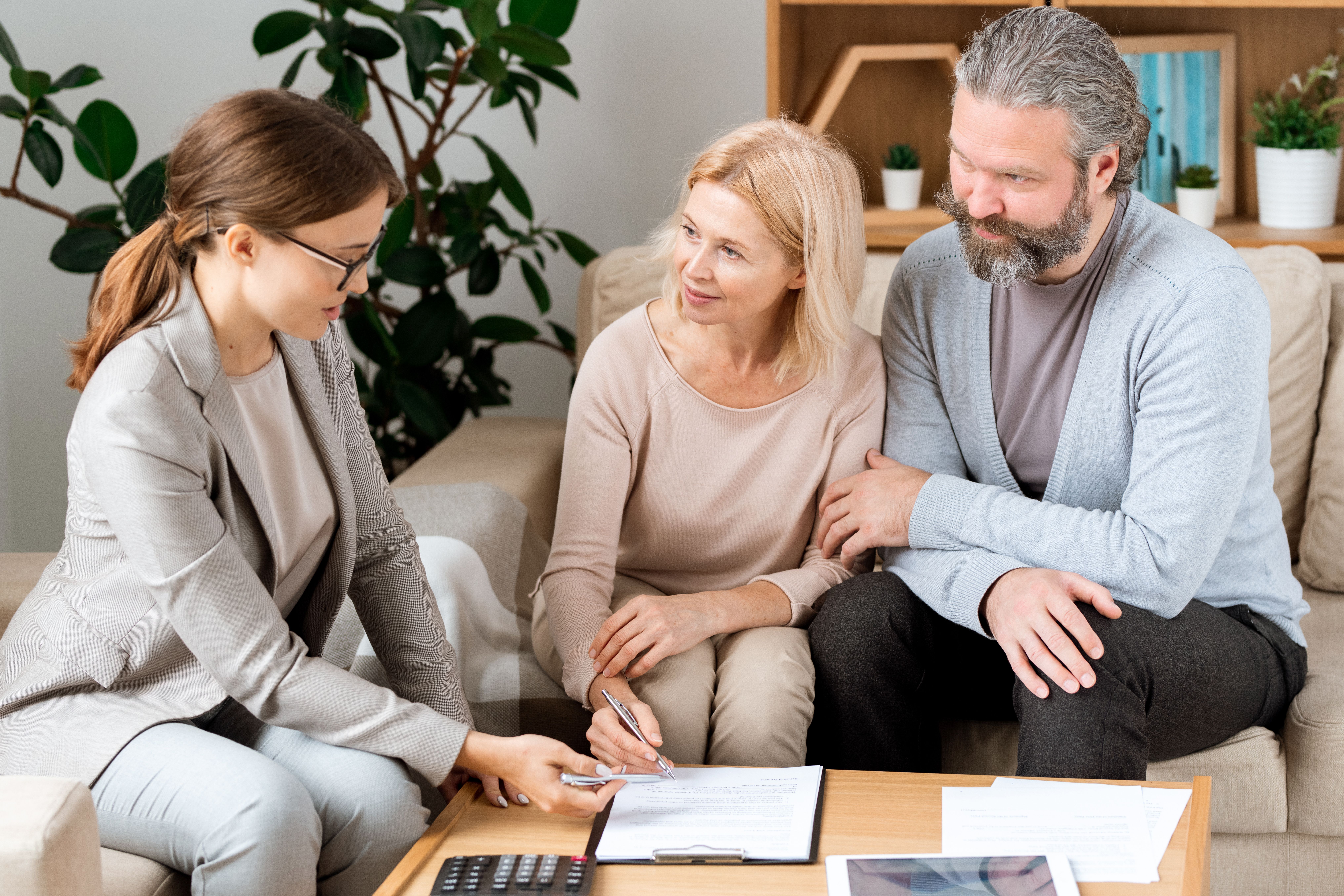 A female real estate and an old couple going through a renewal contract together at a wooden table in a white office with a wooden bookshelf.
.JPG