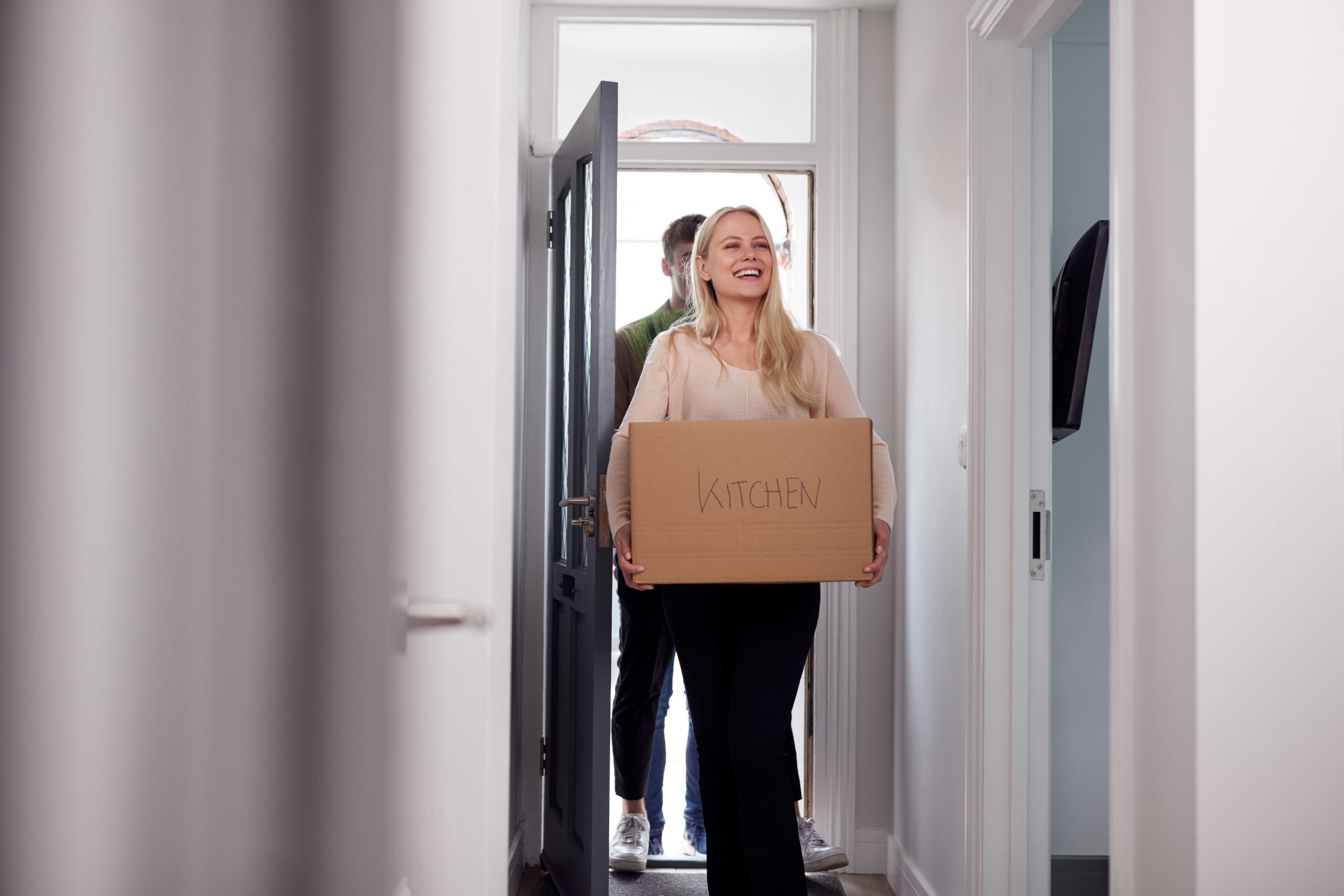 A couple carrying boxes and happily moving into their brand new Build To Rent property.