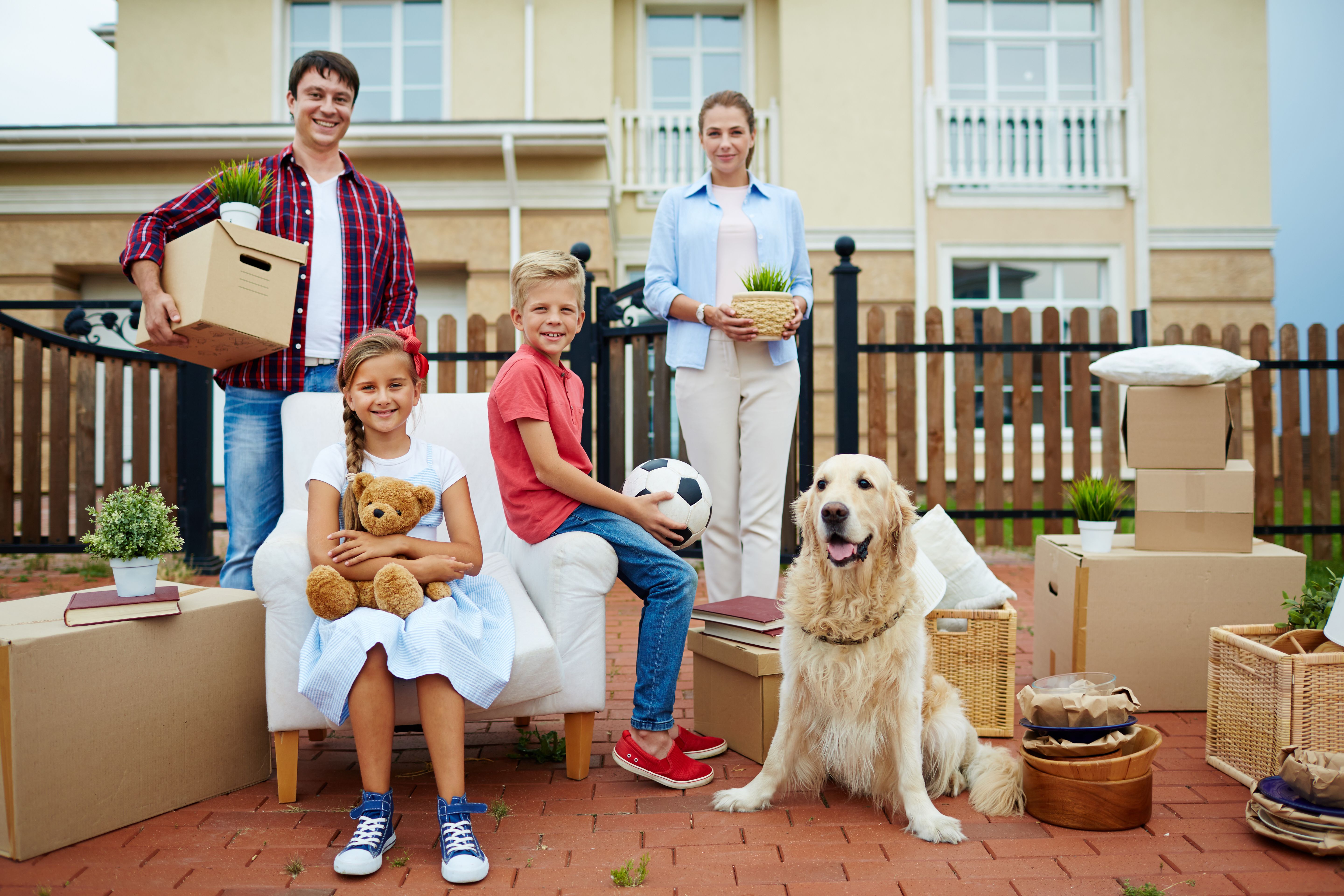 Young couple and their kids gathered in front of a house before moving