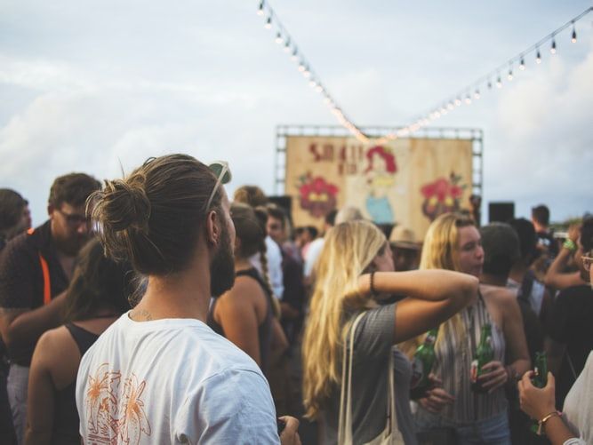 a man standing in a crowd, others girl are talking and drinking together