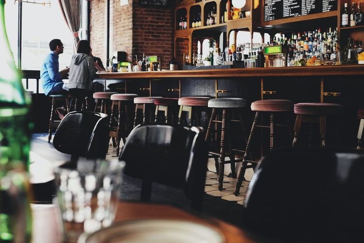 two people sitting on bar stool chair in a bar