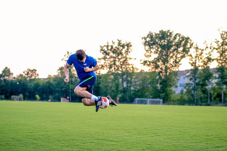 a man wearing blue shirt and playing football