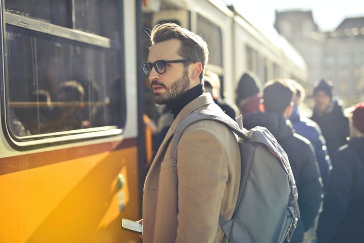 a man wearing brown jacket, waiting for the train