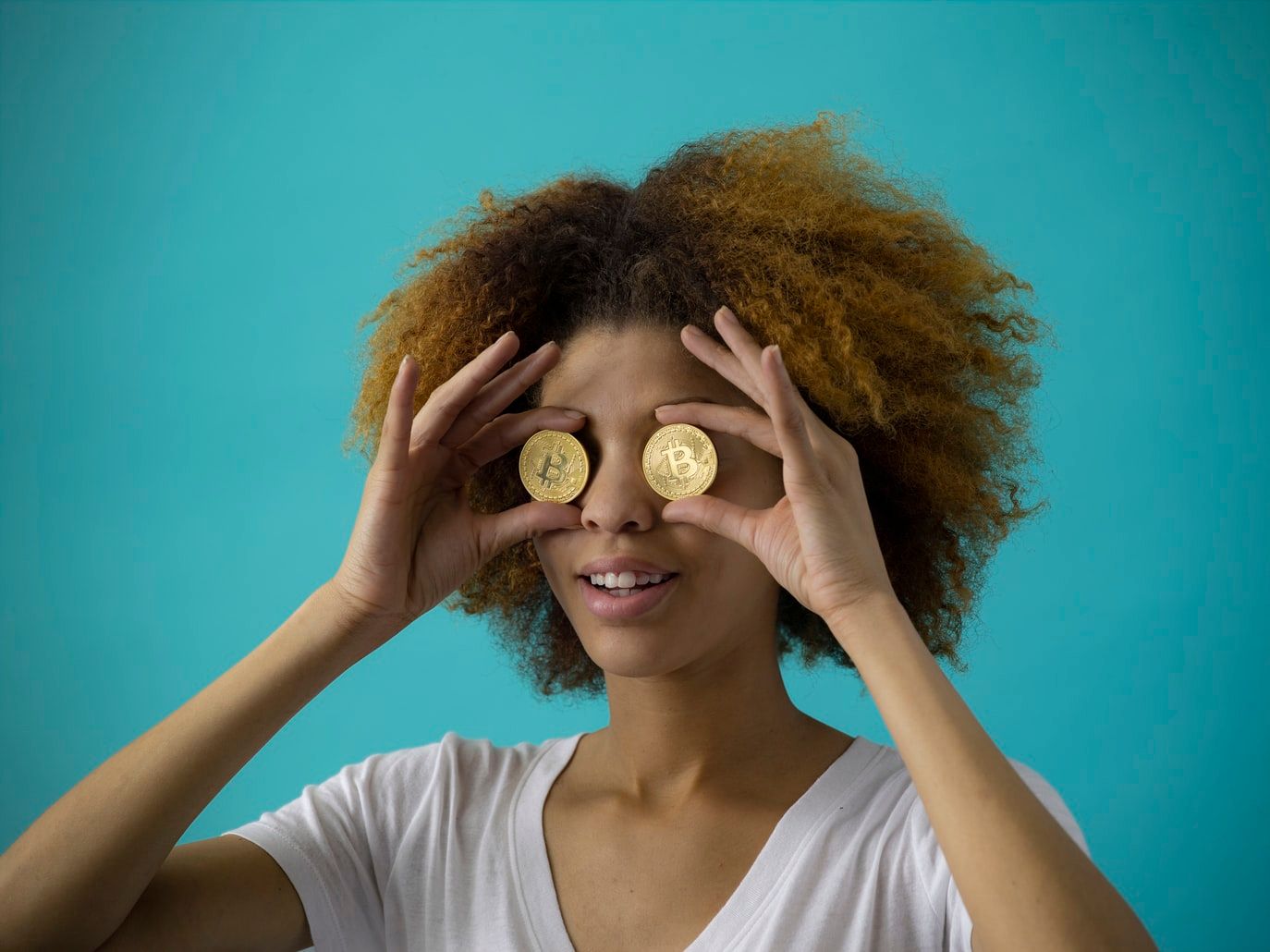 woman holding two round gold-colored coin