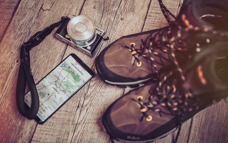 black smartphone beside a camera and boots