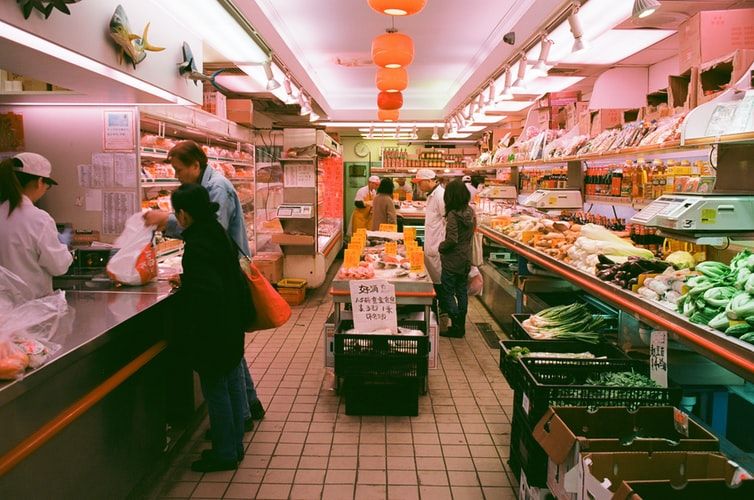 man stands beside another man in front of cashier in a supermartket