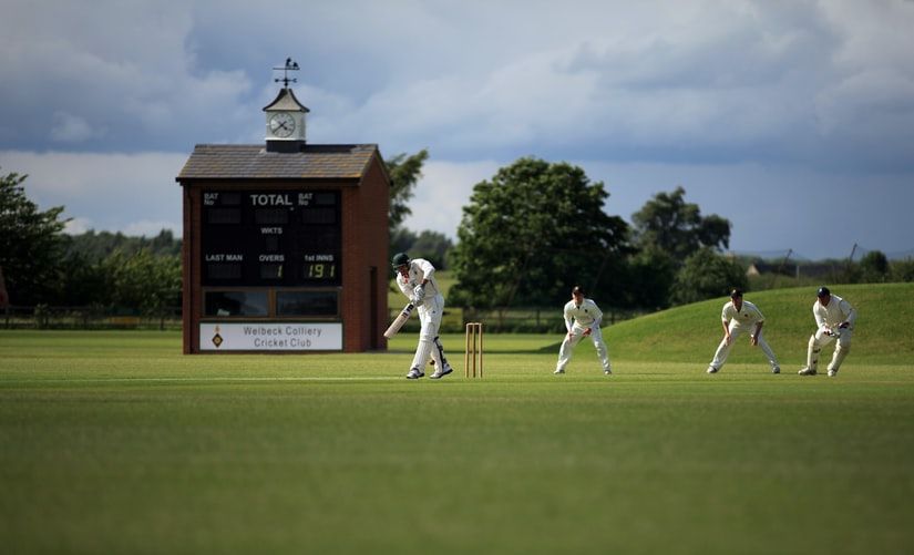 a group of people wearing white uniform and playing cricket together