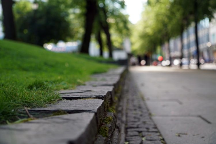 gray concrete road near a green grass