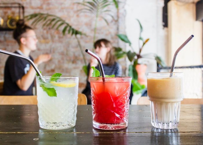 Three assorted drinks in glasses with straws