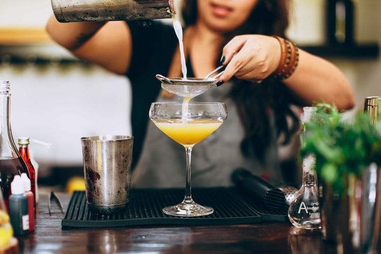 a woman in black sleeveless top holding clear cocktail glass