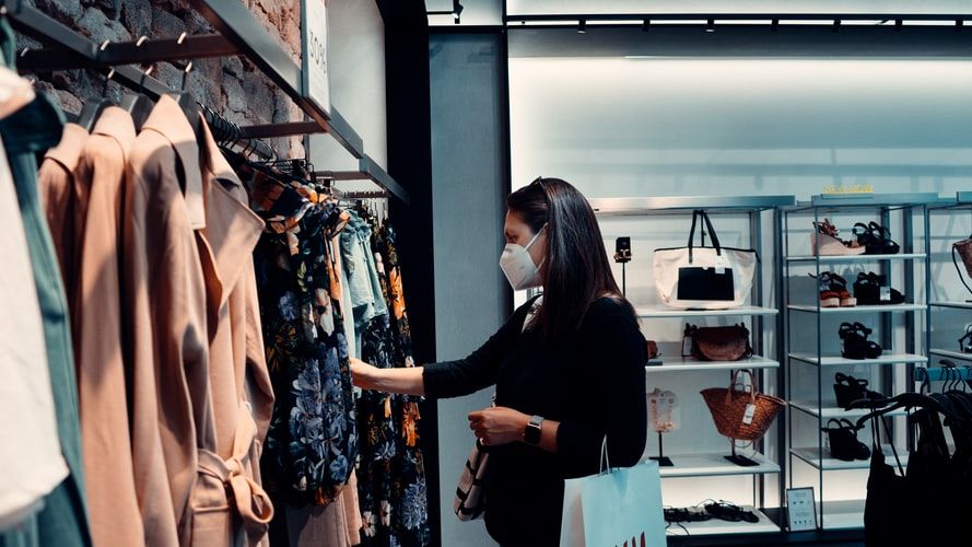 a woman in black long sleeve shirt standing in front of clothes display rack