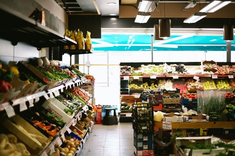 a corner of grocery store, fresh fruits and vegetable are displayed in baskets