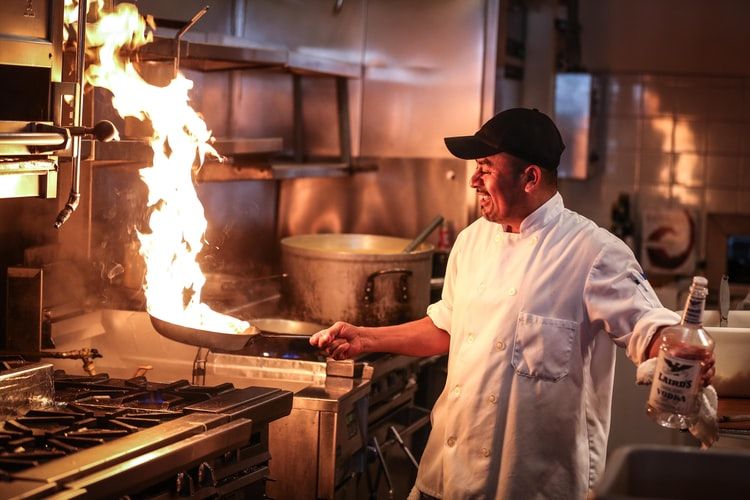 a man in white chef uniform cooking in a restaurant