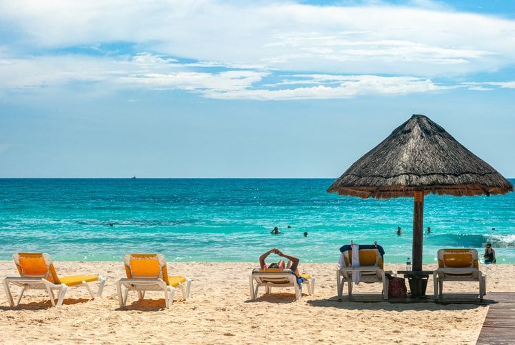 brown beach umbrellas on the beach, yellow chairs surrounded