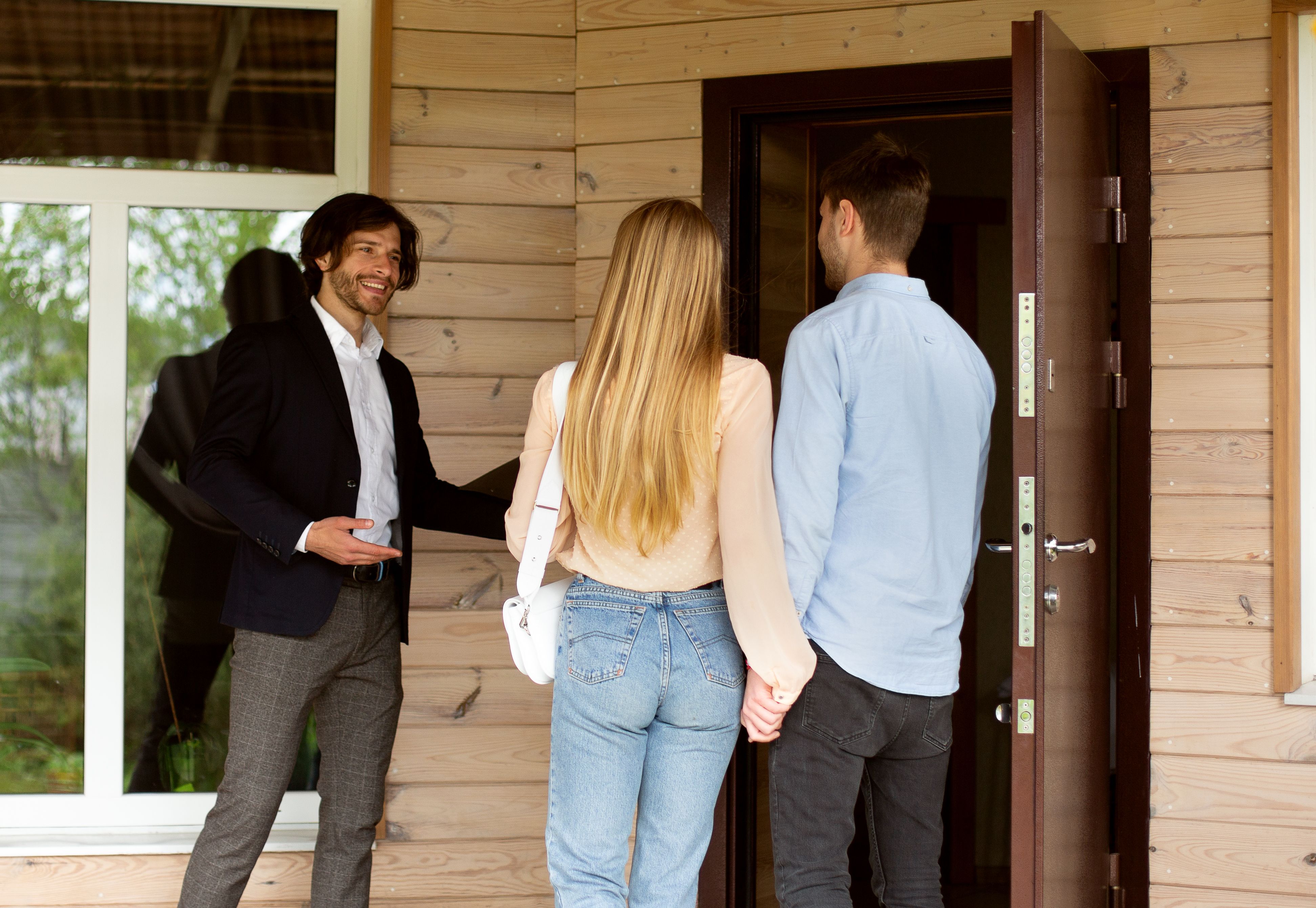 During a property viewing, a letting agent invites potential buyers to enter a house for sale