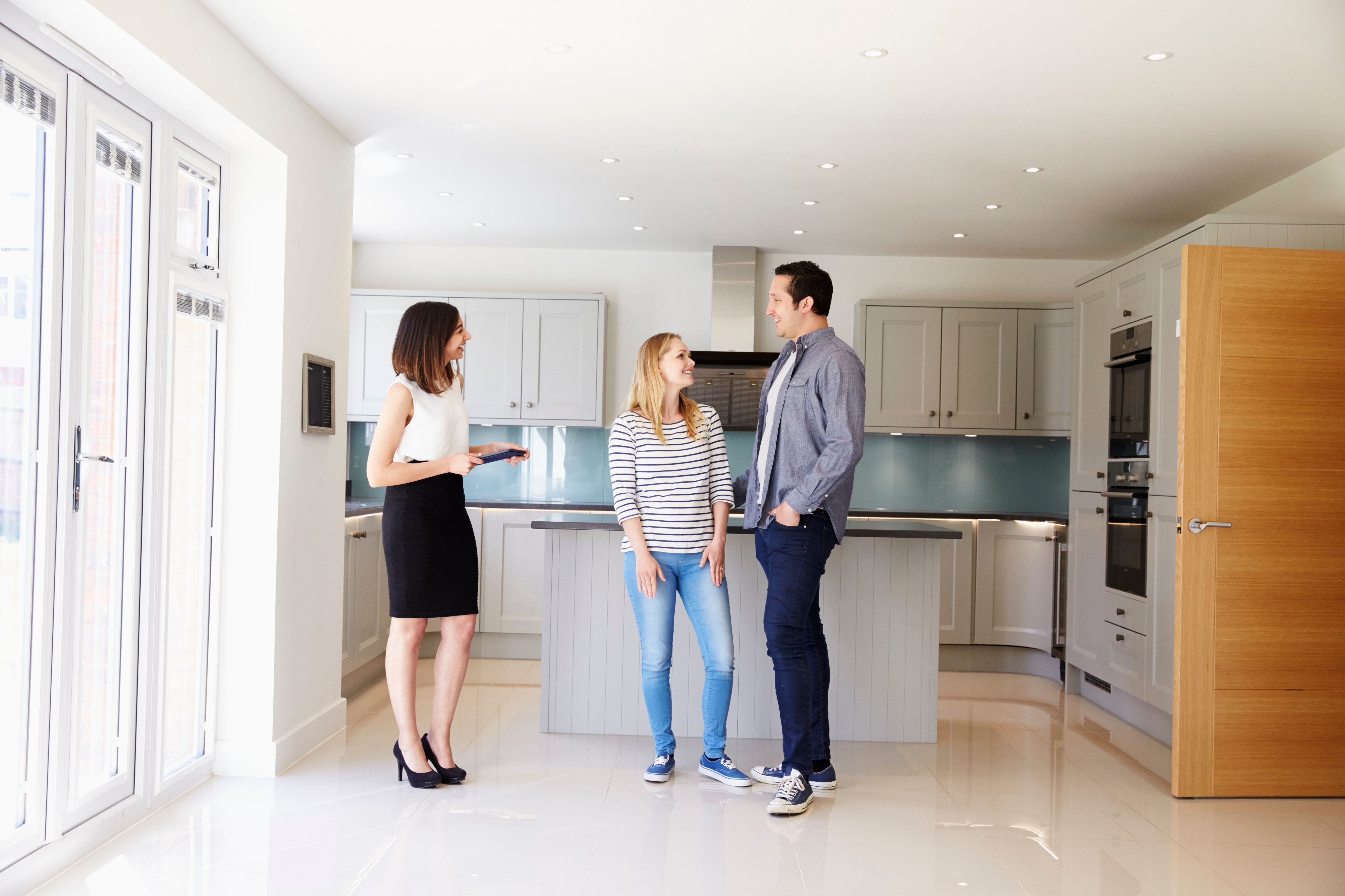 realtor showing young couple around property.jpg