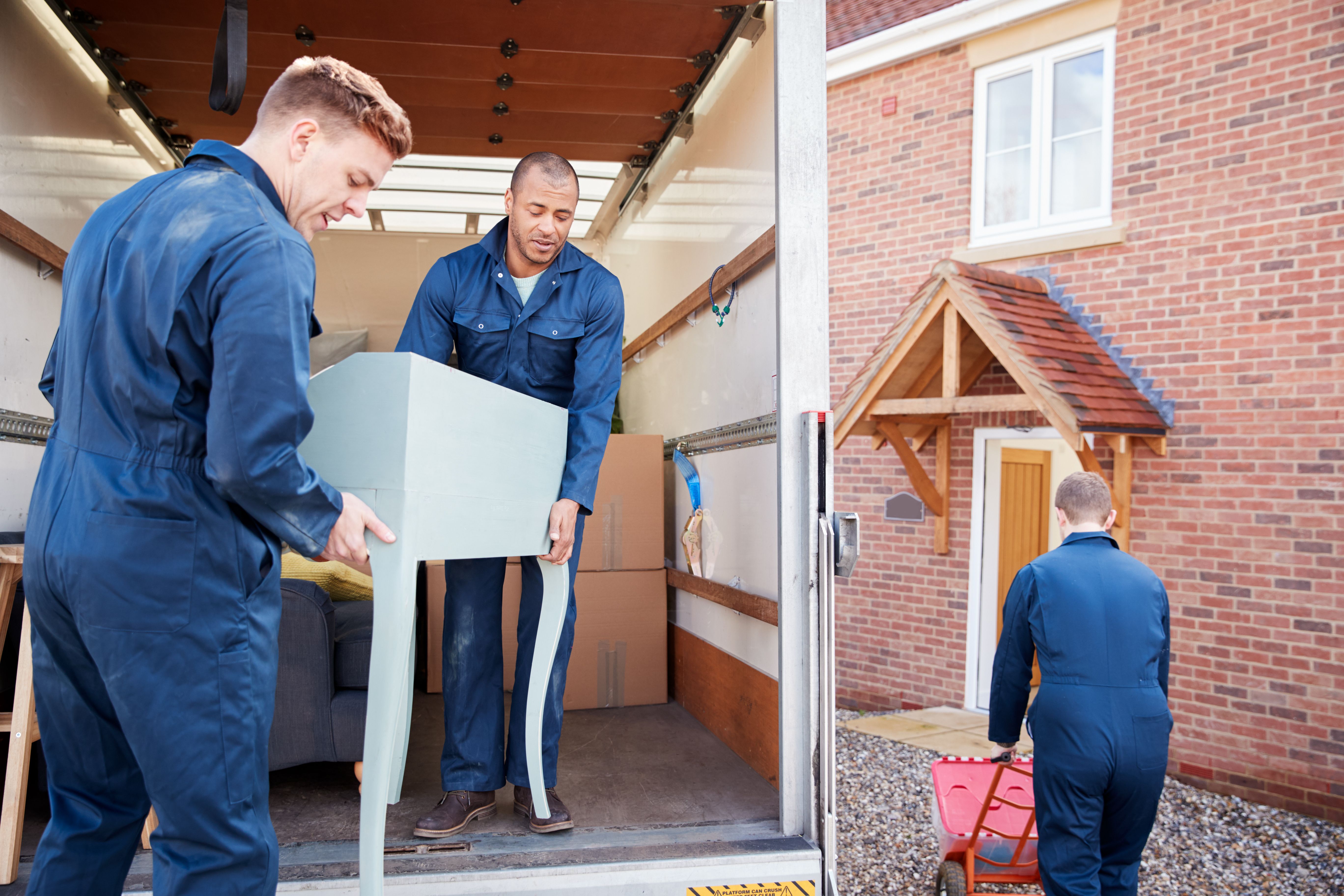 Removals workers unloading furniture and boxes from a truck