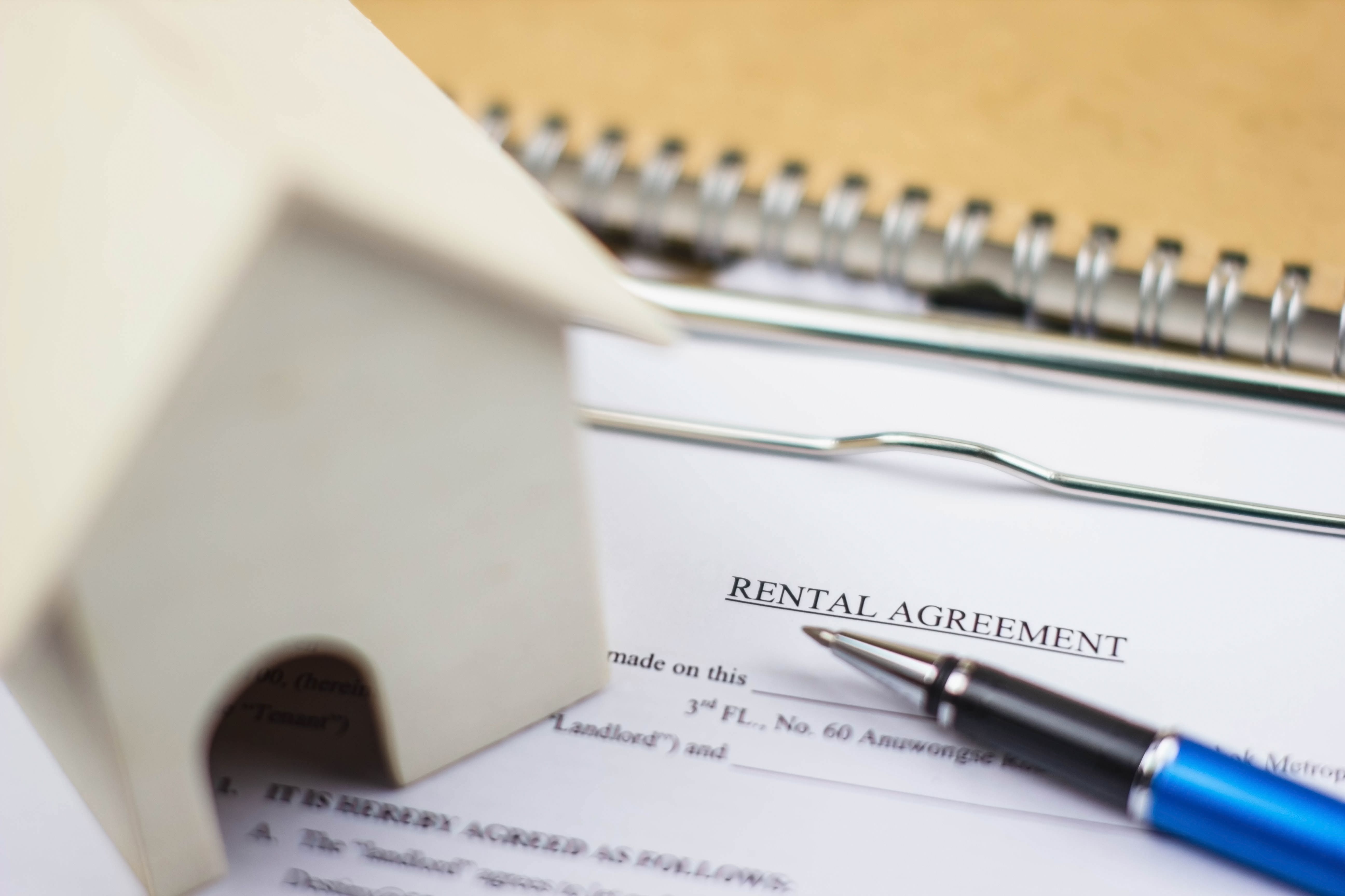 A rental agreement underneath a house model contains terms of living and rental cost at a Build To Rent property.