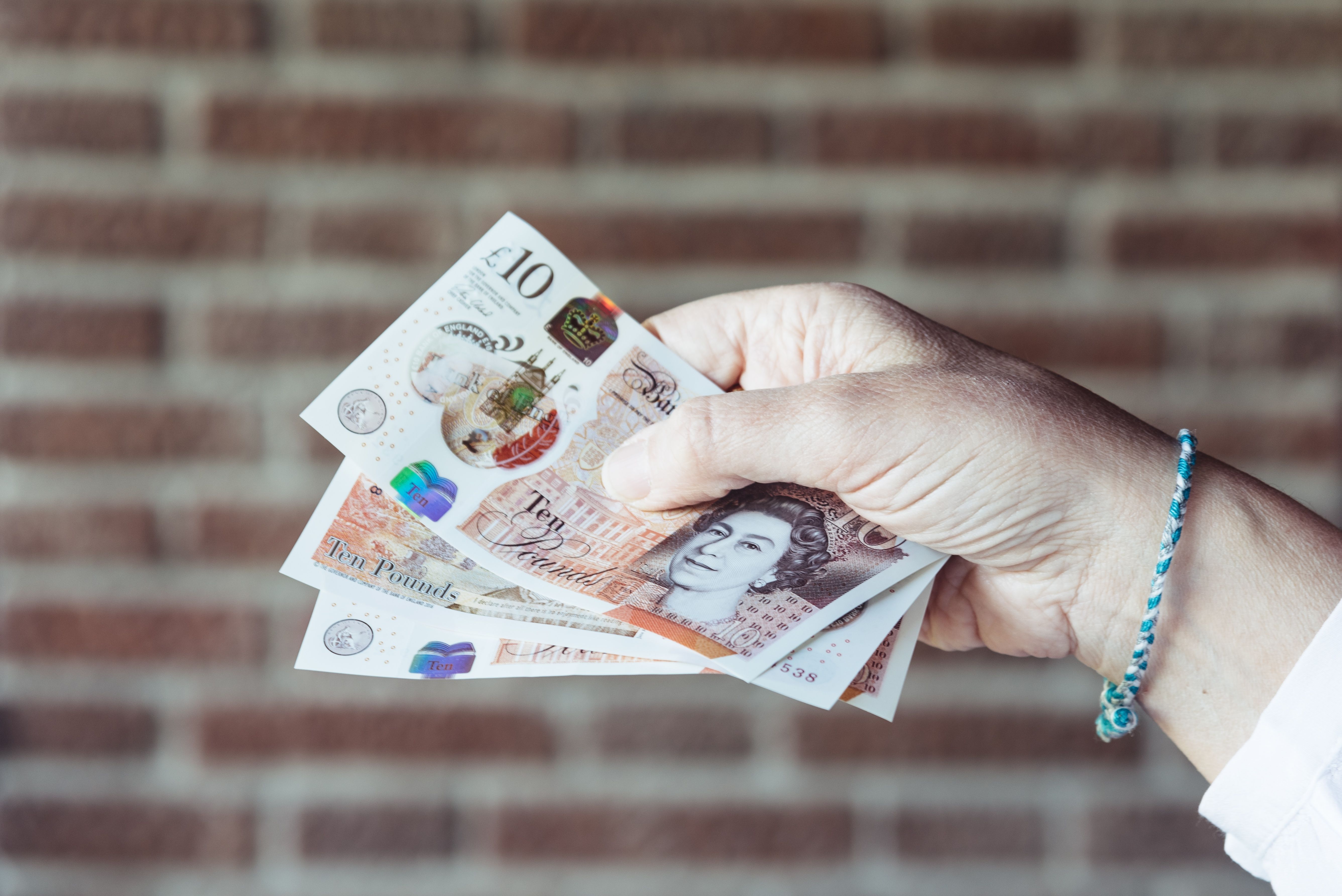 A woman holding British pounds against background