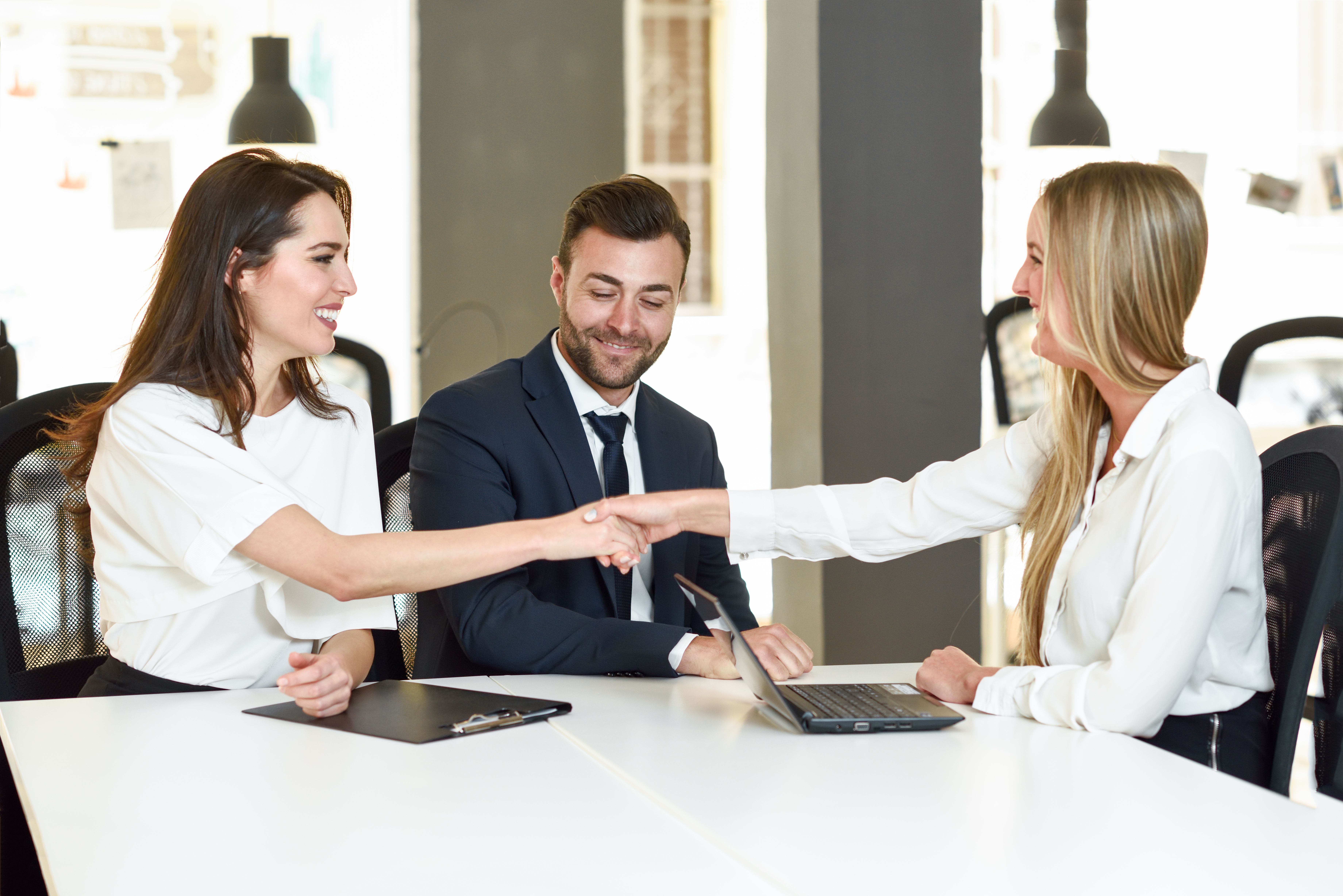 A smiling young couple shaking hands with an insurance agent