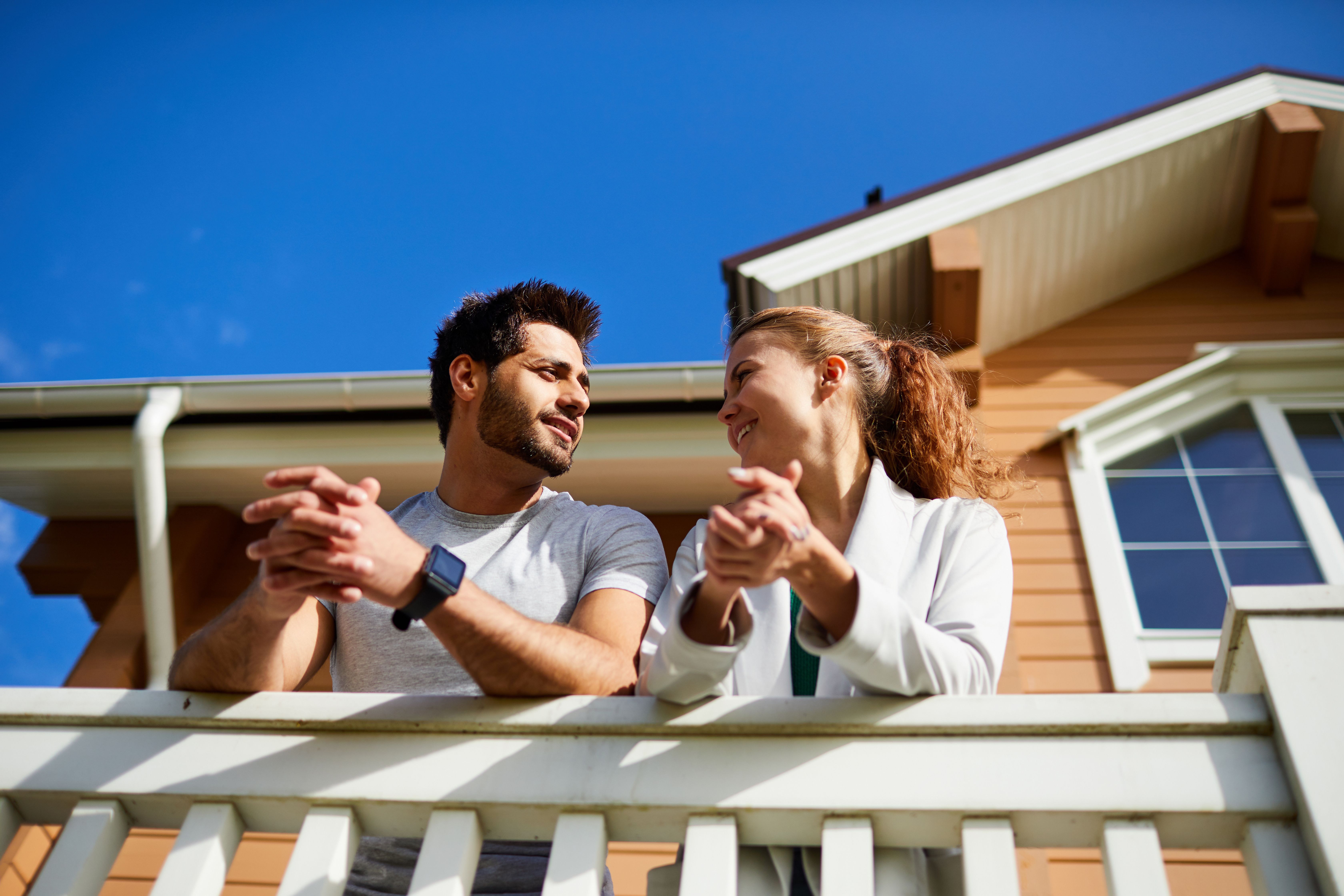 A couple talking passionately in their home balcony at a new build development to rent.