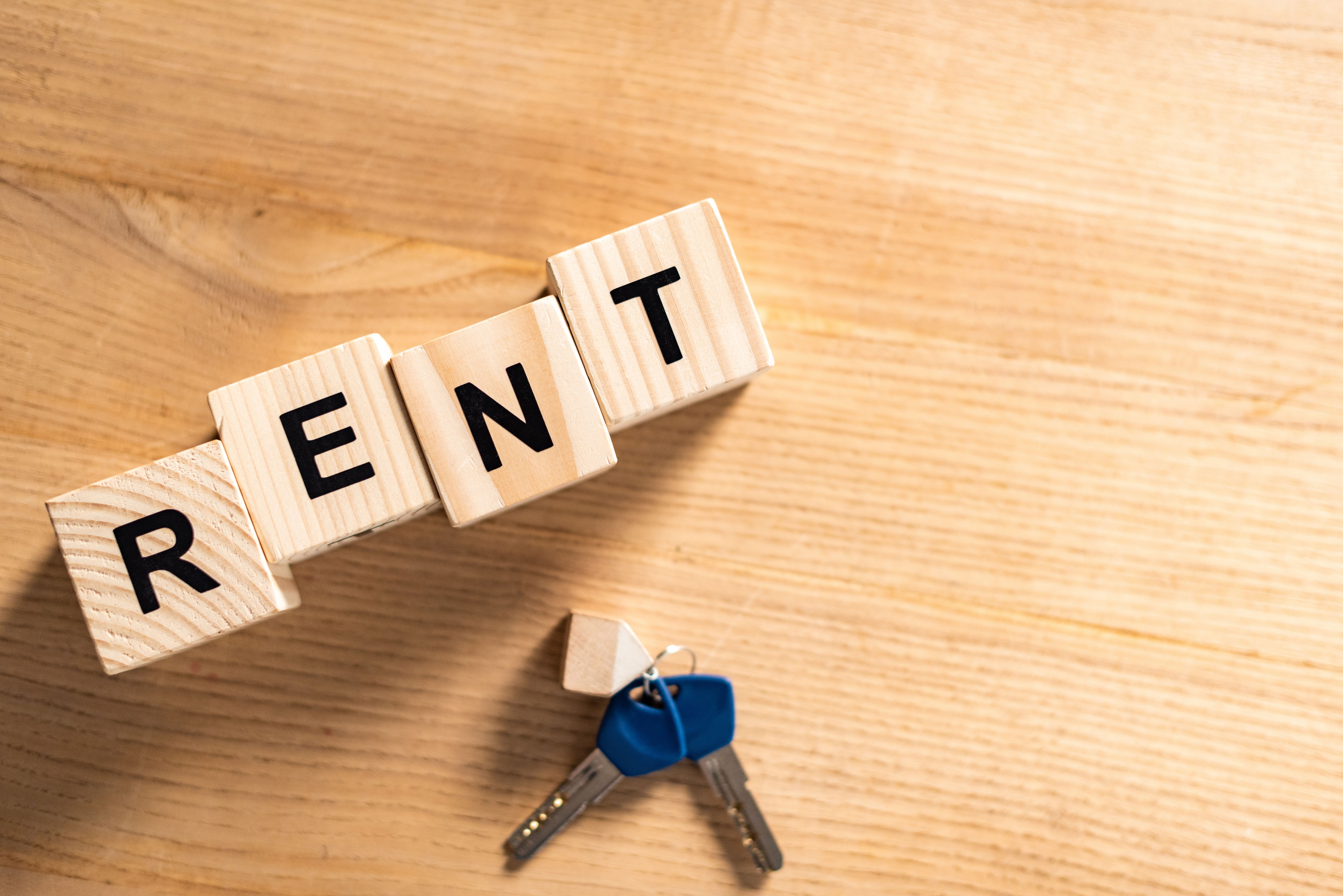 Top view of keys with a keychain near wooden cubes with rent lettering on table