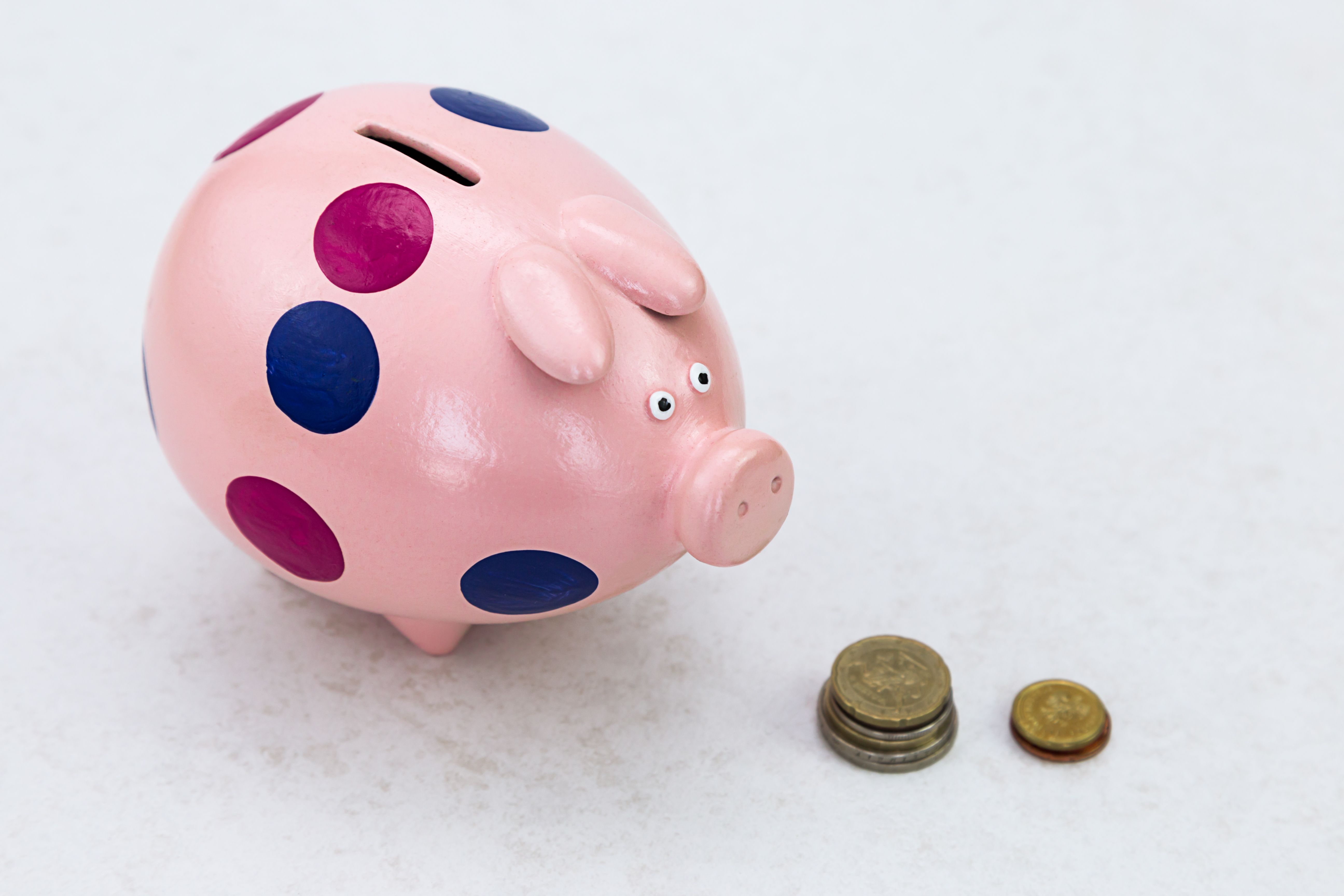 A piggy bank with coins on a light background