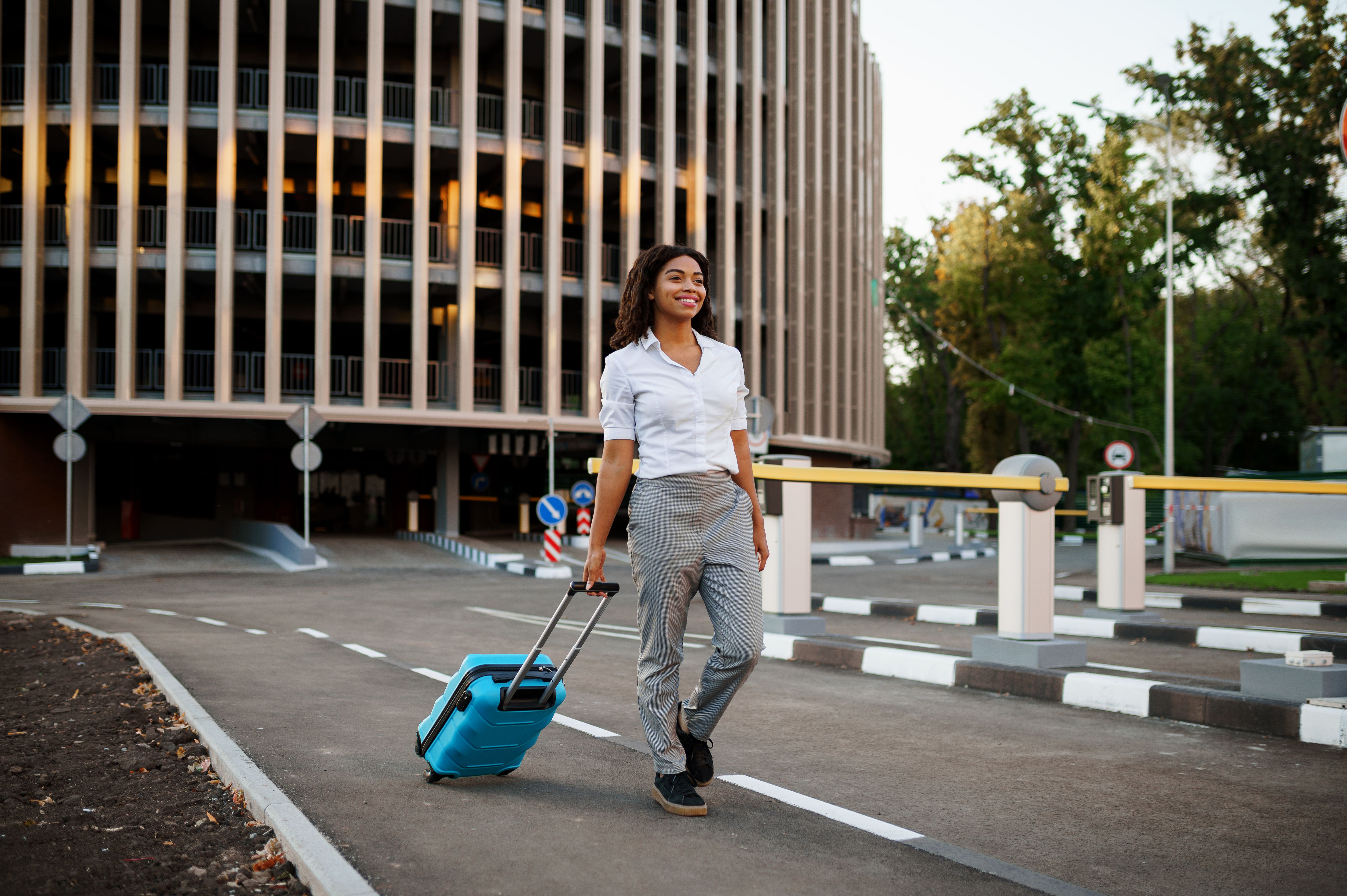 woman with suitcase at the entrance to car parking