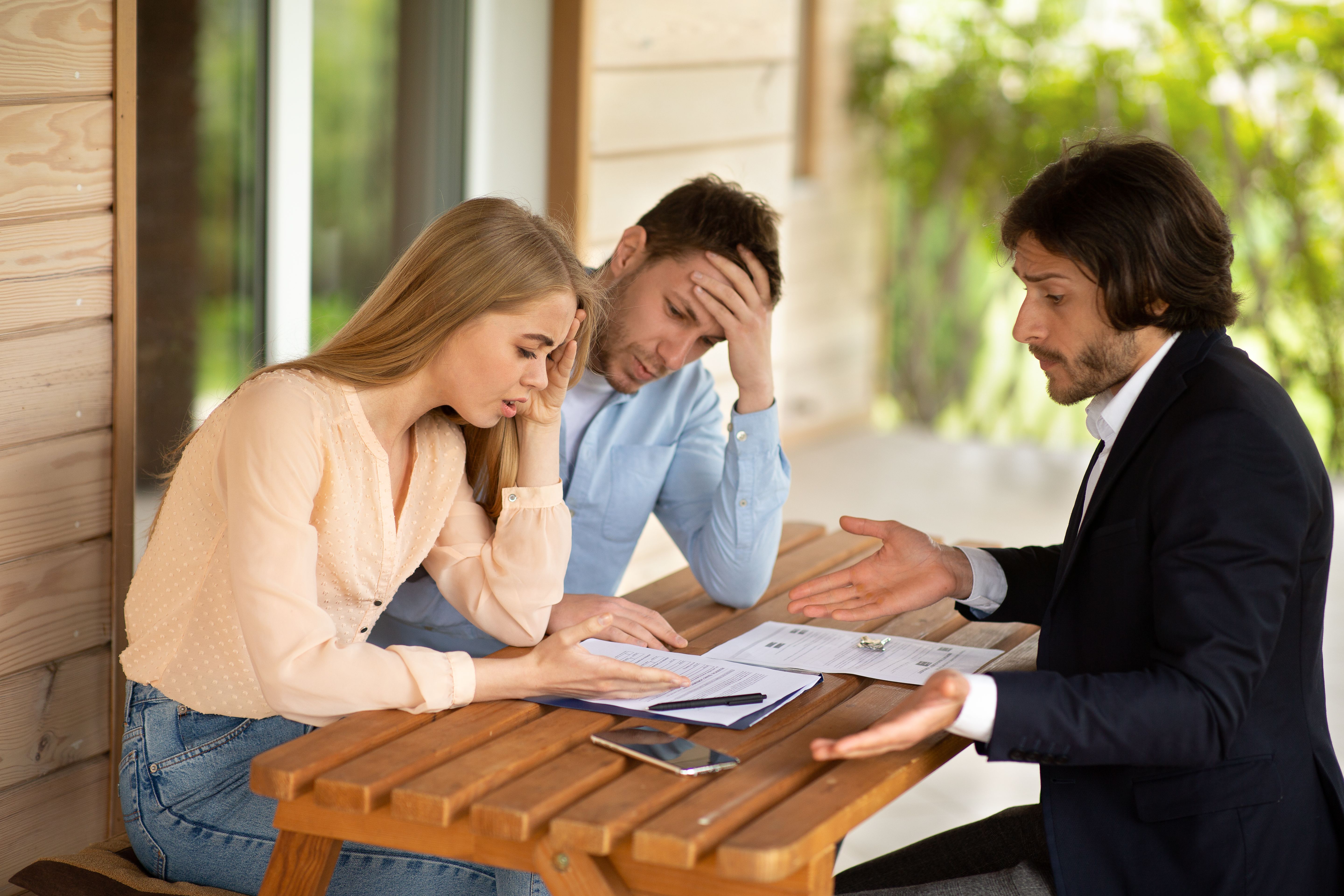 A young couple dissatisfied with tenancy agreement terms and a letting agent in front of a house