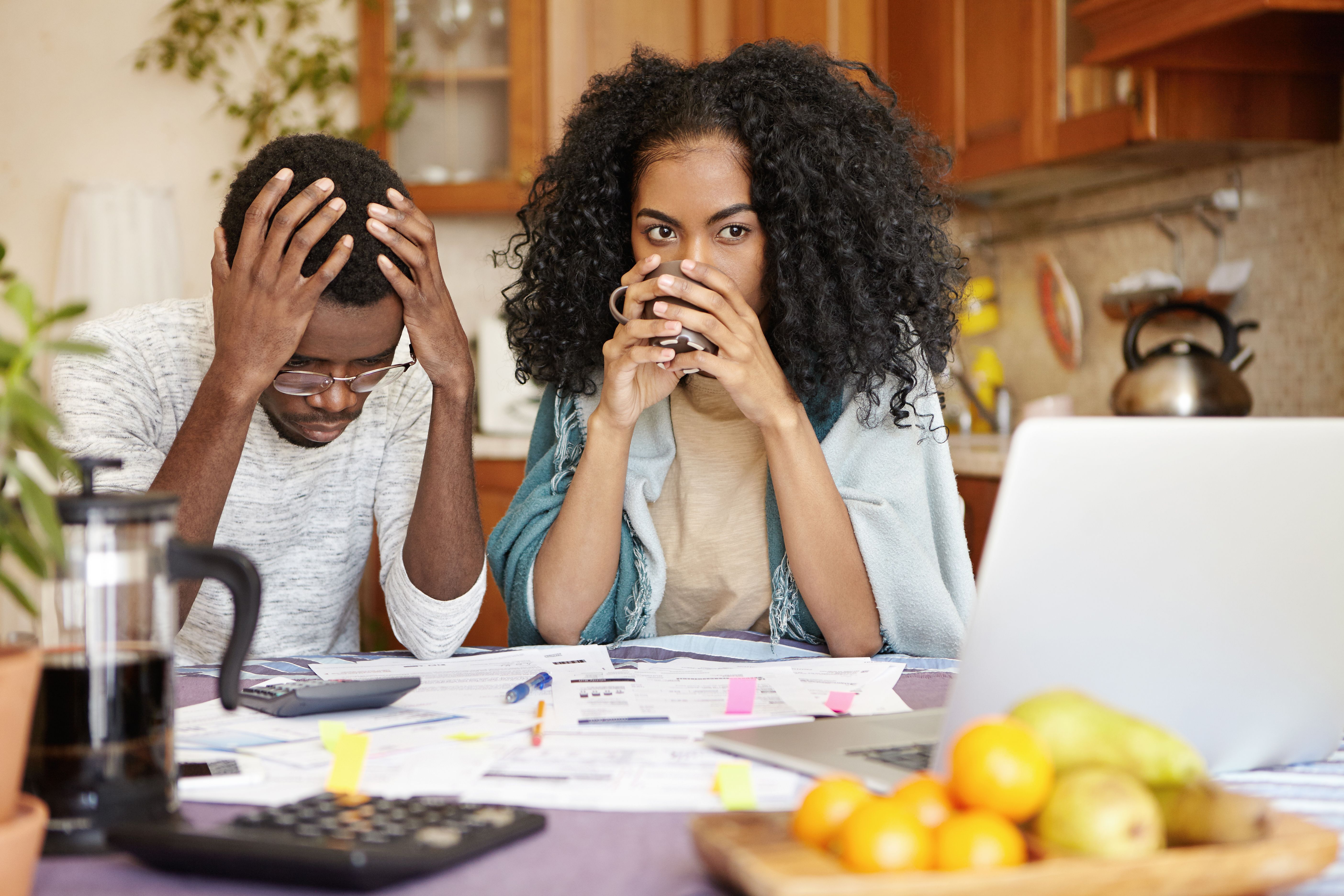 A worried couple sitting at a table looking at documents