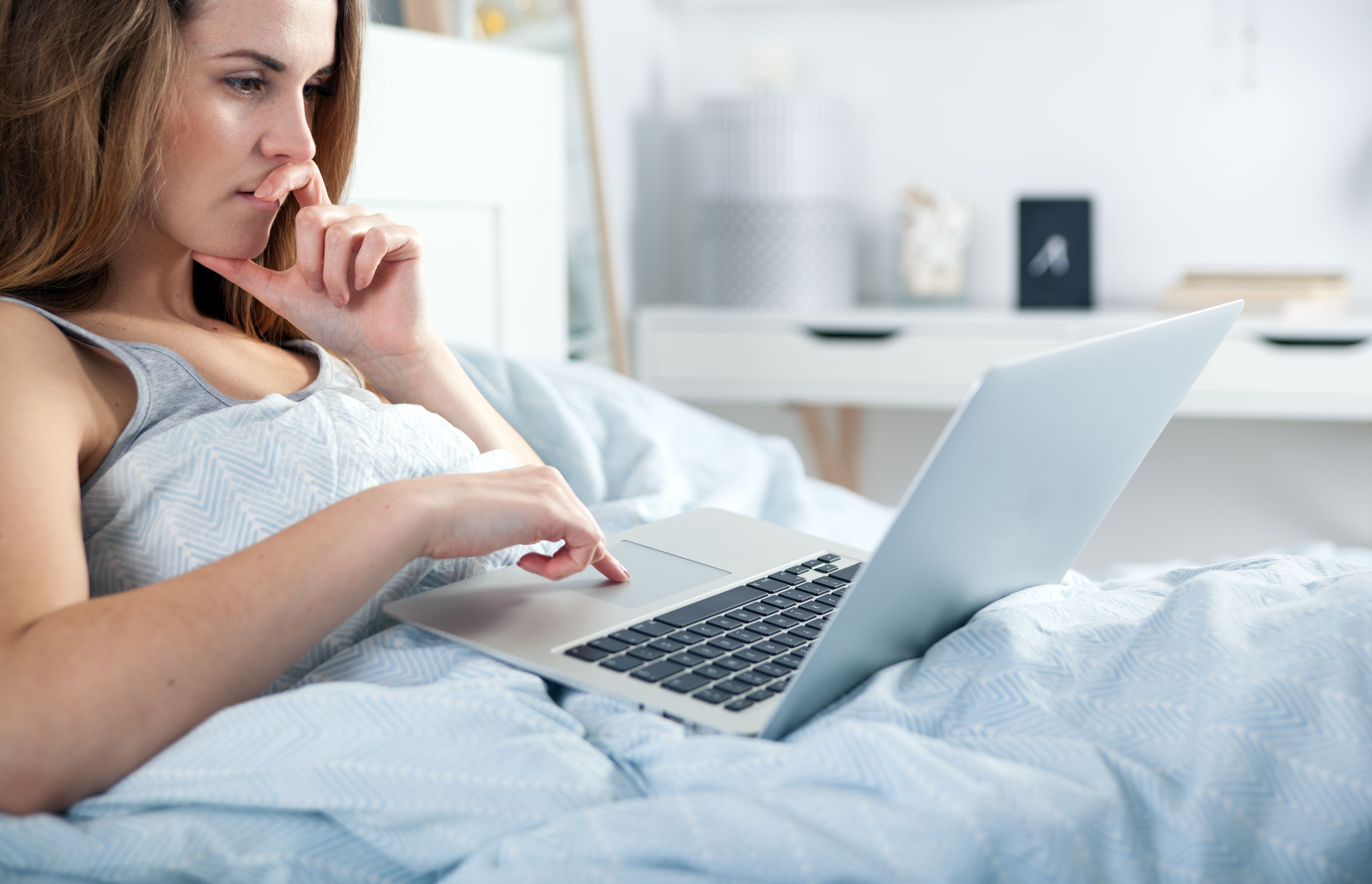 A woman looking at a laptop in a bed