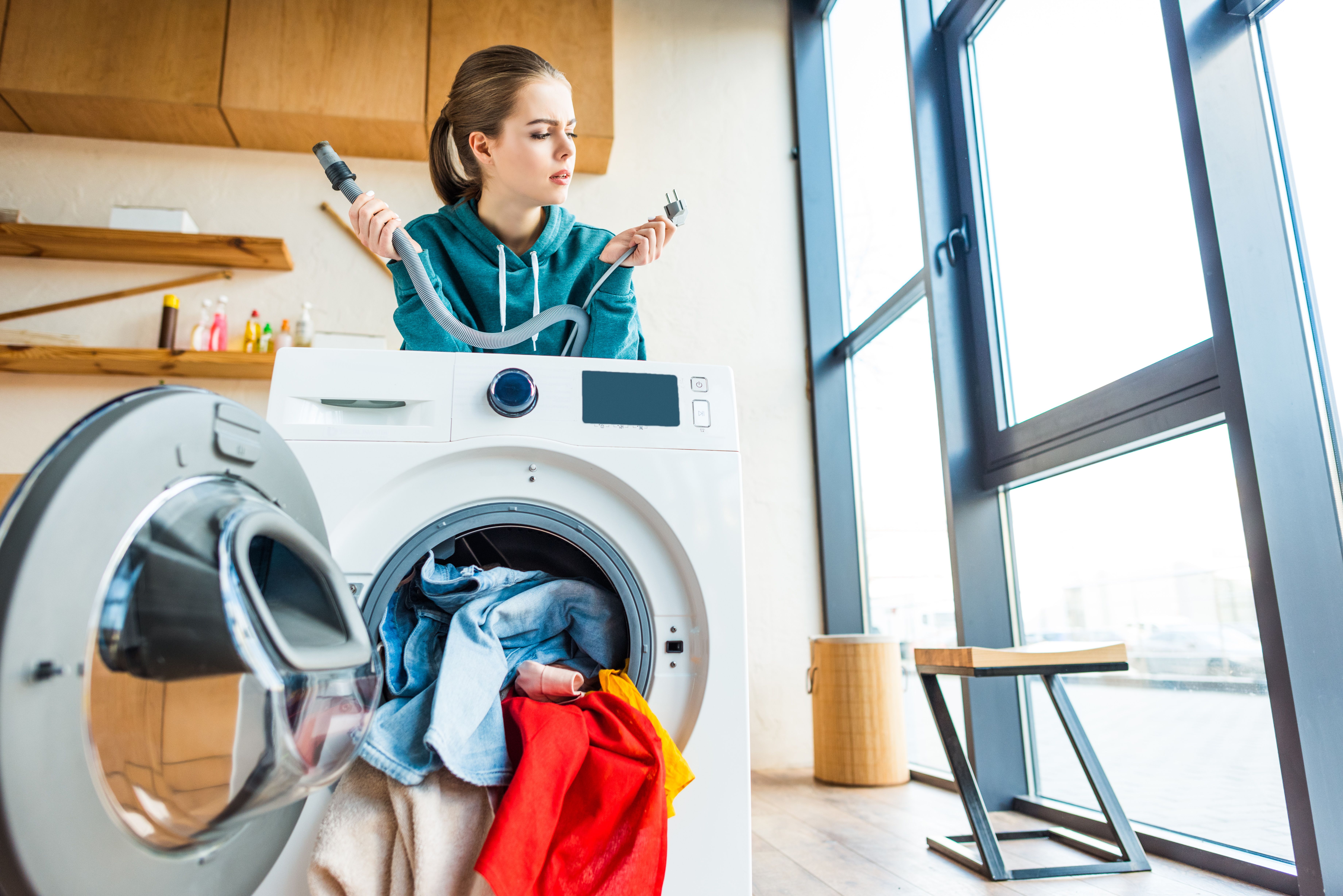 A young woman leaning at a broken washing machine