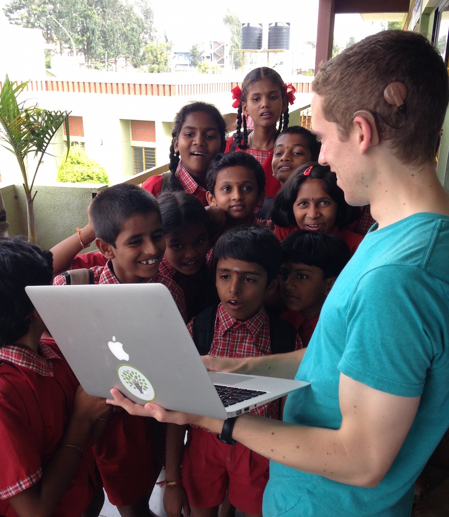 Erik showing his laptop to 10 excitedly peering deaf children