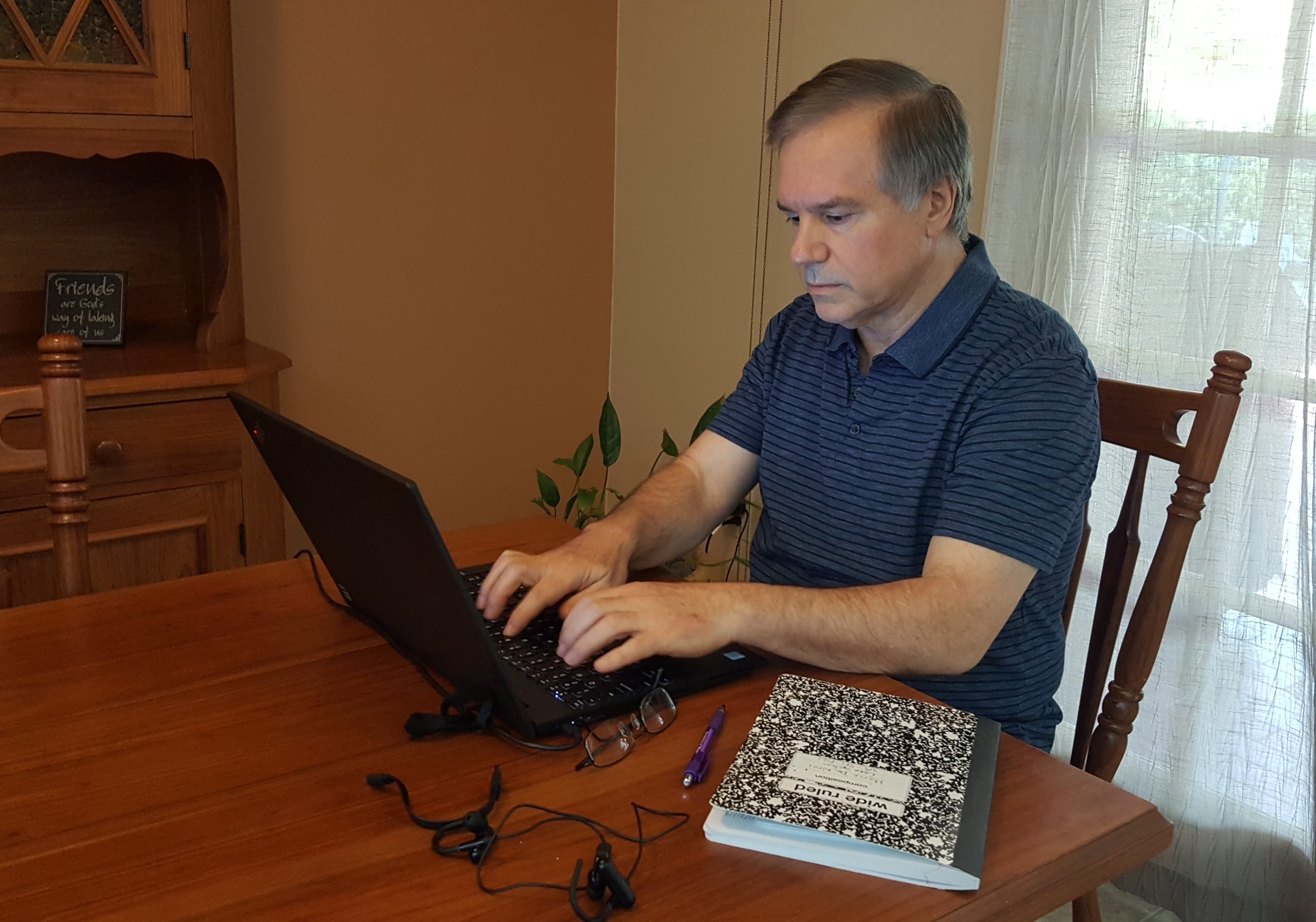 Mario De Novi sits at his kitchen table working at his computer.