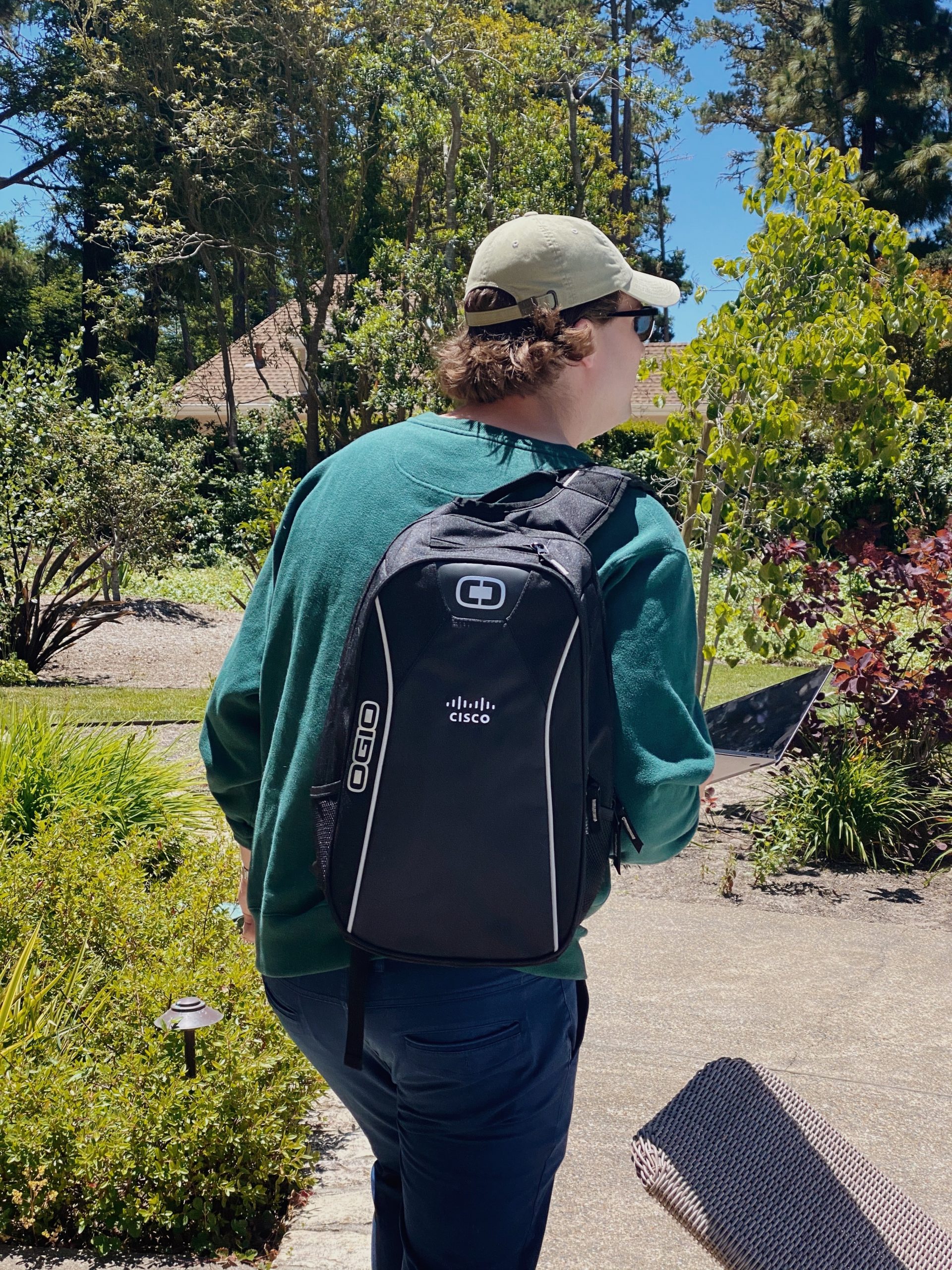 Matthew walks away from the camera with a Cisco branded backpack 