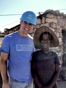 A man in a hardhat smiling for the camera with a woman wearing a straw hat